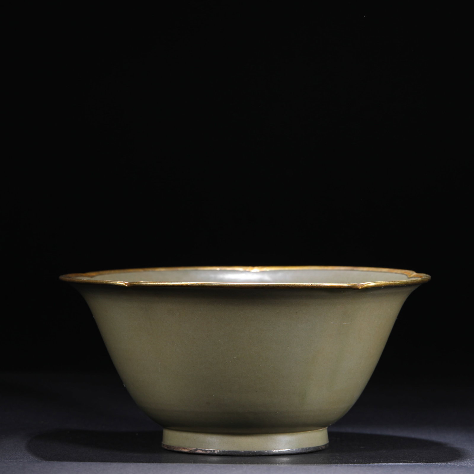 A GREEN GLAZED FLOWER-MOUTHED BOWL FROM THE SONG DYNASTY'S LONGQUAN KILN: H:8.2cm(3.23in)W:18.3cm(7.20in) This Song-Yuan period Longquan kiln celadon flower-mouthed bowl, with a warm bean-green glaze, delicate flower-mouthed shape, and gilded rim and silver-inlaid foot, is 