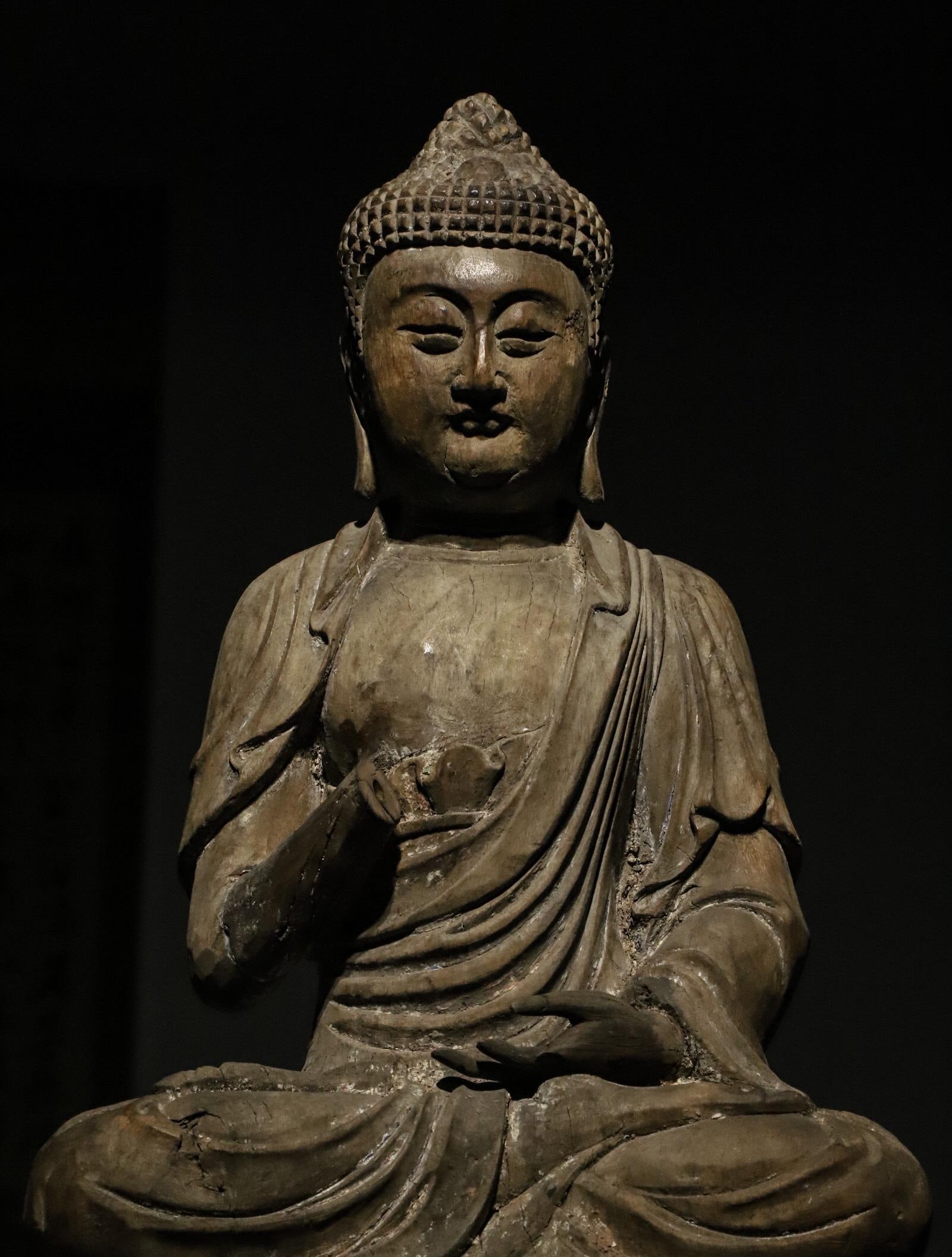 A SEATED STATUE OF SAKYAMUNI MADE OF NANMU WOOD FROM THE MING DYNASTY: H:46cmL:26cmW:20cm The style of this statue combines the solemnity of the Ming Dynasty statues with the secular characteristics of the Qing Dynasty statues. It is a typical representative of the trans