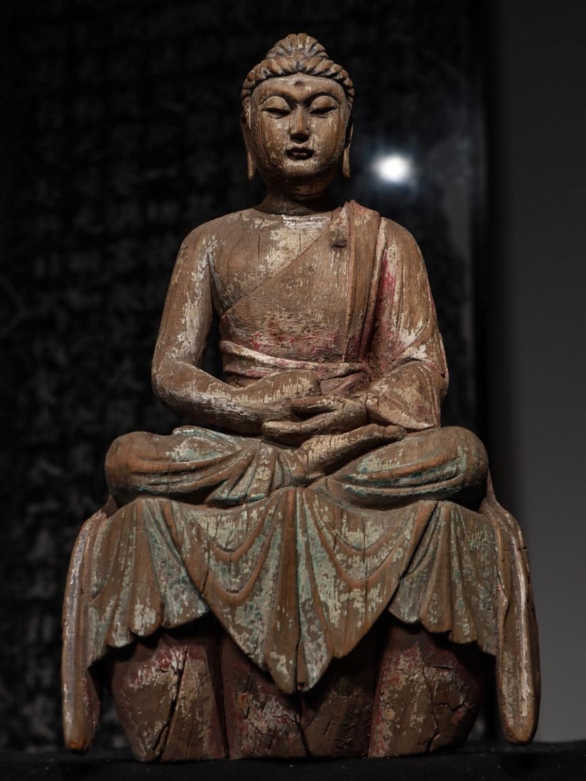 A WOODEN STATUE OF SAKYAMUNI FROM THE MING DYNASTY: H:38cmL:23cmW:15cm Sakyamuni Buddha is the founder of Buddhism. This statue is not only a carrier of religious beliefs, but also a tangible witness of the deep integration of ancient Chinese woodcarvi
