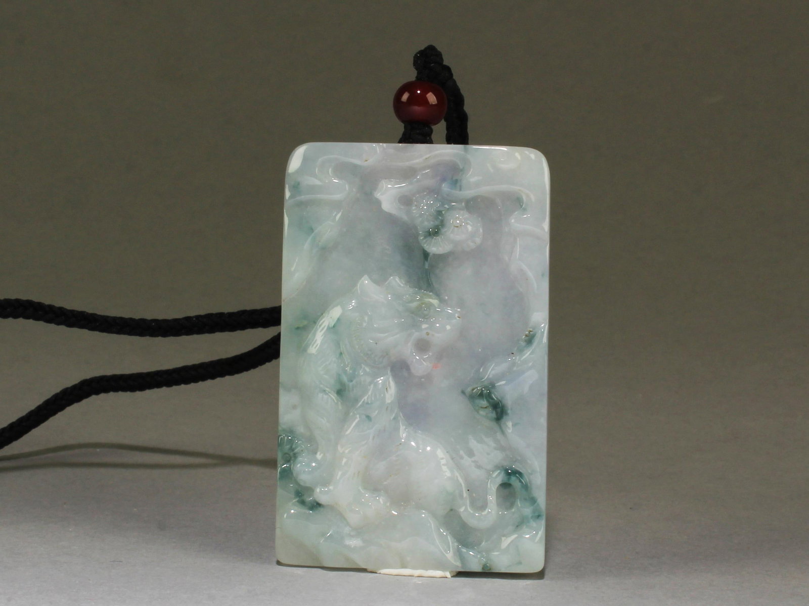 Chinese Jade Pendant: The rectangular shaped pendant is carved in relief of tiger on both sides, attached to bead tied to a string. Height: 2.5"