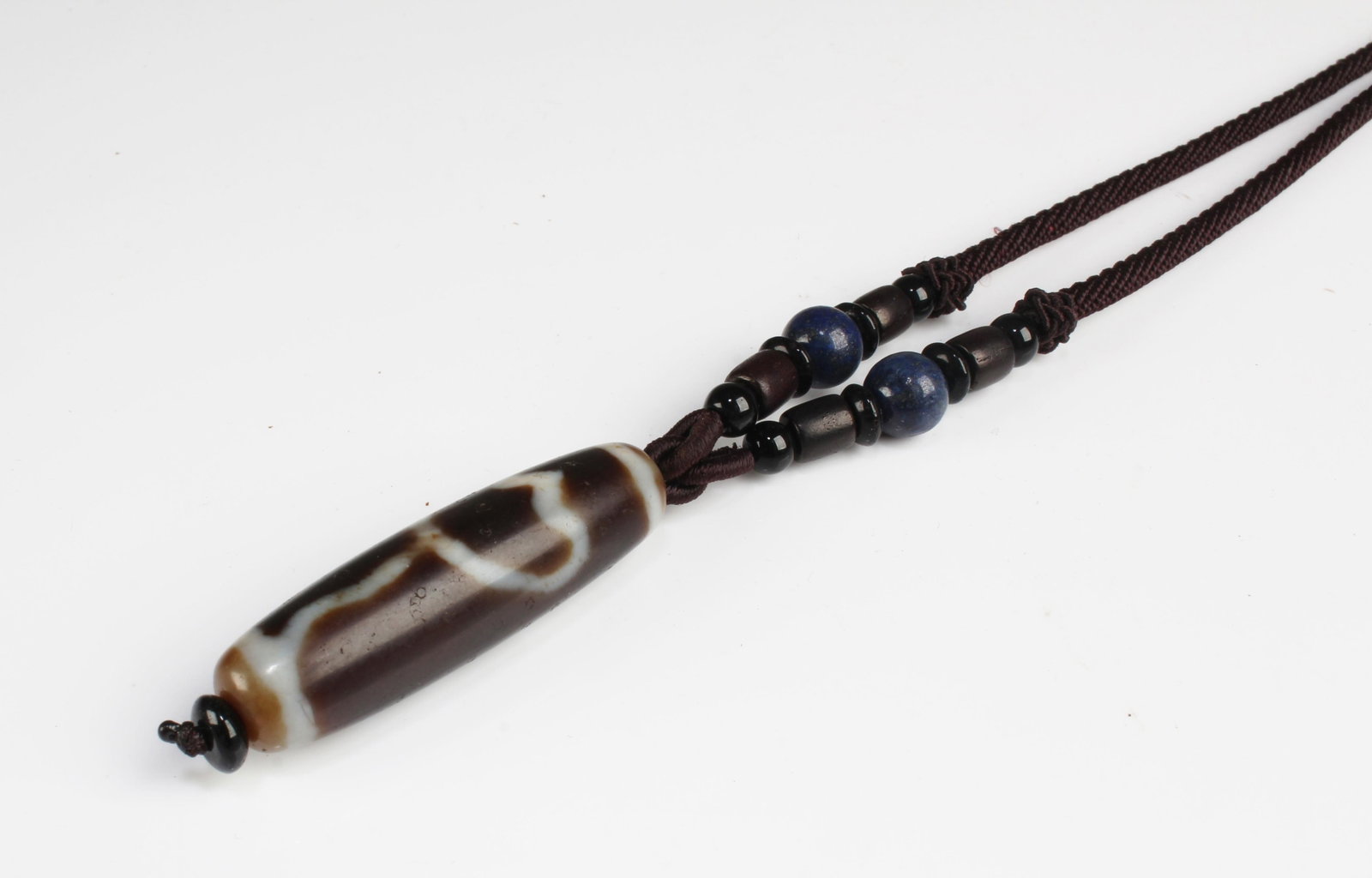 A Dzi Bead Necklace: A Dzi Bead, attached to a cord strng necklace. Length: 1.75" (Dzi)