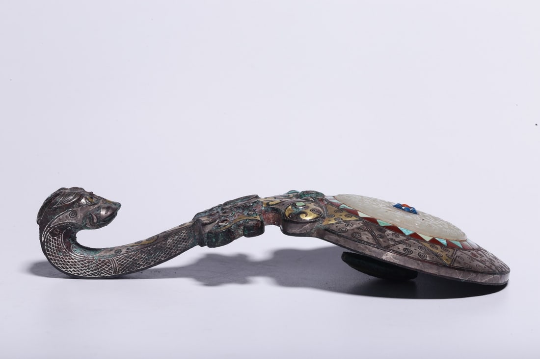 A Bronze Inlaid Gold and Silver Turquoise-Inlaid Beast-Head Belt Hook: A Bronze Inlaid Gold and Silver Turquoise-Inlaid Beast-Head Belt Hook. Dimensions: 1.38in x 6.97in x 2.56in; Weight: 0.94lbs.