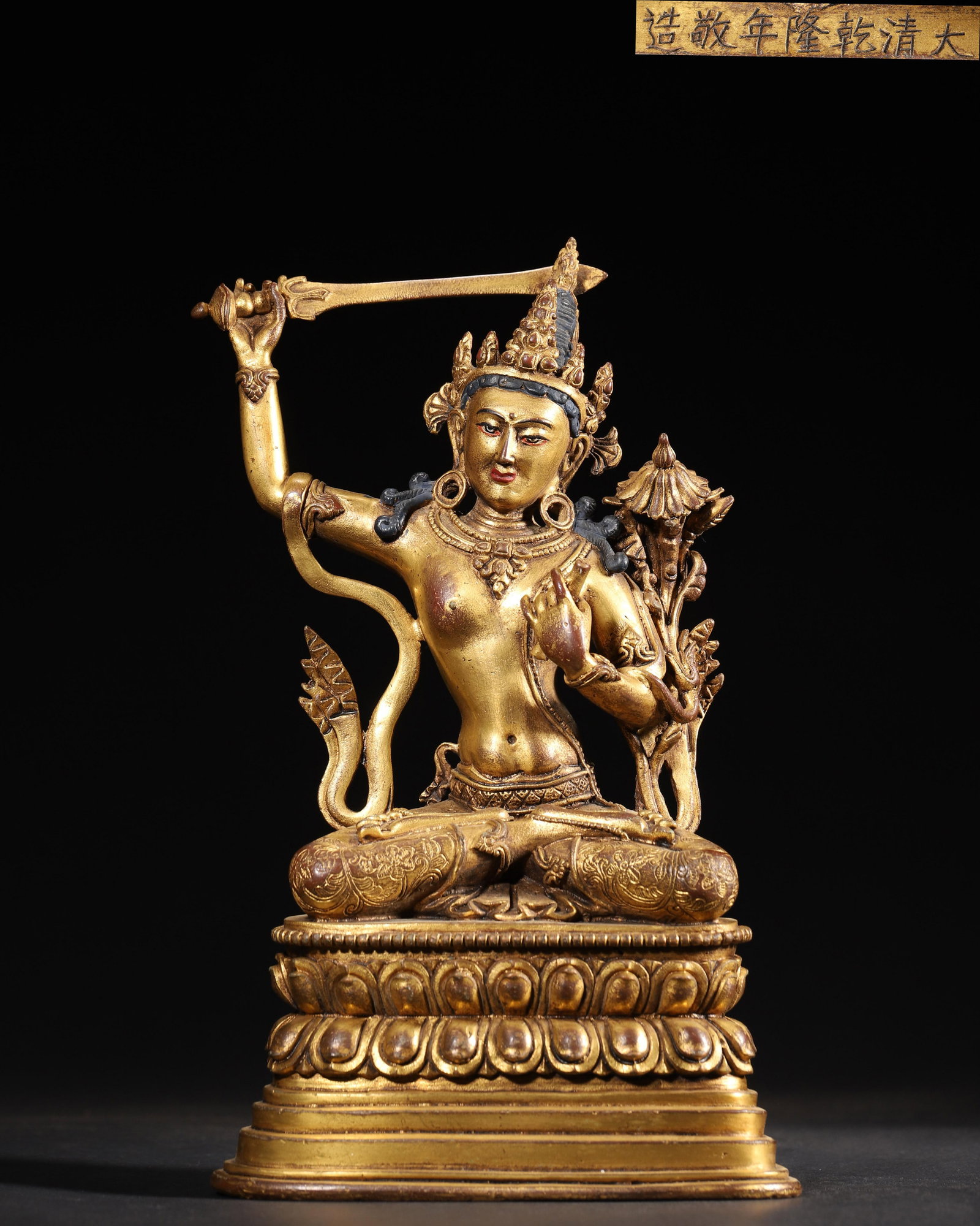 IMPERIAL COMMISSIONED GILT-BRONZE FIGURE OF MANJUSHRI, QING DYNASTY, QIANLONG PERIOD: 6.3" x 3.94" x 10.24" inches (16.0 cm x 10.0 cm x 26.0 cm) (Main) | Weight: 4.29 lbs (1944.0 g)A fine imperial gilt-bronze figure of Manjushri, Qianlong period, Qing Dynasty. Exquisitely cast with ric