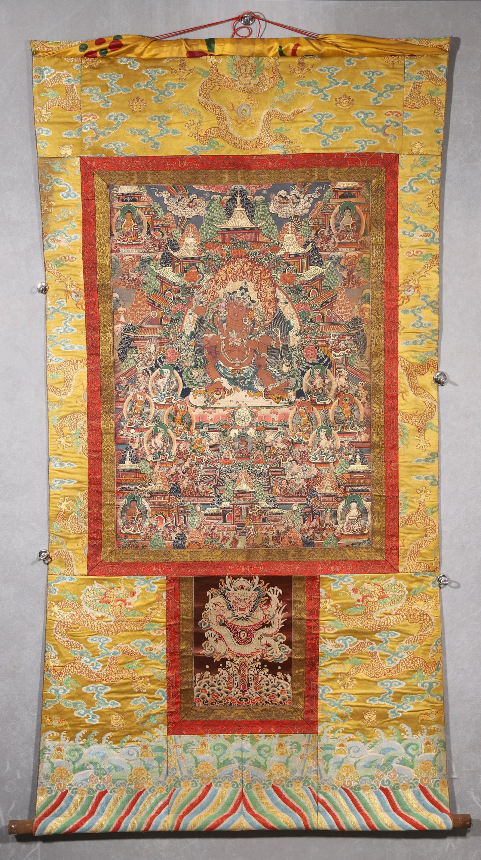 A Yellow Jambhala Thangka - Qing Dynasty: Length 80.0cm (31.5in), Width 57.0cm (22.44in)This Qing Dynasty thangka depicts Yellow Jambhala, painted with mineral pigments on cotton. The central wealth deity sits serenely with a mongoose, surrou