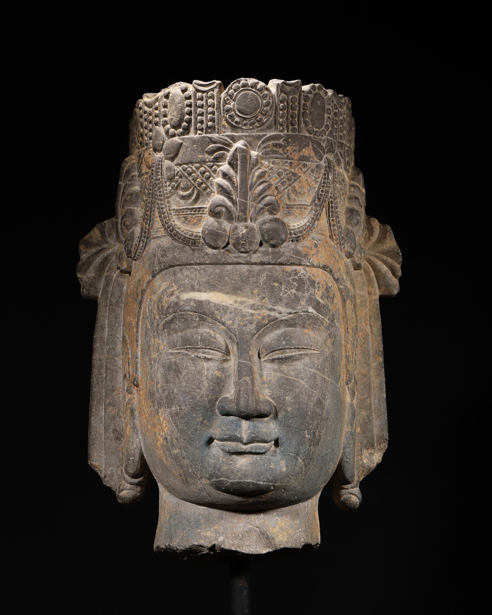 TANG DYNASTY BLUE-STONE CARVED BODHISATTVA HEAD (WITH RESIDUAL PIGMENTS): 11.81 x 9.84 x 15.75 in (30 x 25 x 40 cm), 77.16 lbs (35000 g)A fine Tang Dynasty blue-stone carved Bodhisattva head, with a serene expression and elaborate headdress. Residual blue and ochre pigments