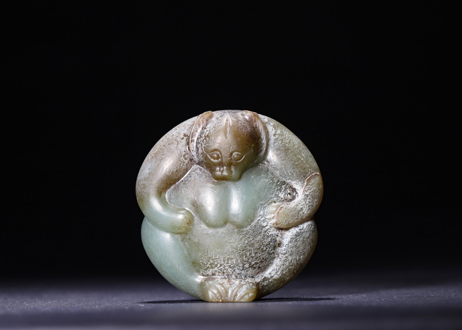 AN ARCHAIC JADE MYTHICAL BEAST PENDANT: H 6.00cm (2.36 in); L 5.8cm (2.28 in); W 3.00cm (1.18 in); Wt 159.00g (0.35 lb);,This archaic pendant is carved from celadon jade as a curled mythical beast, covered with natural white ancient patina 