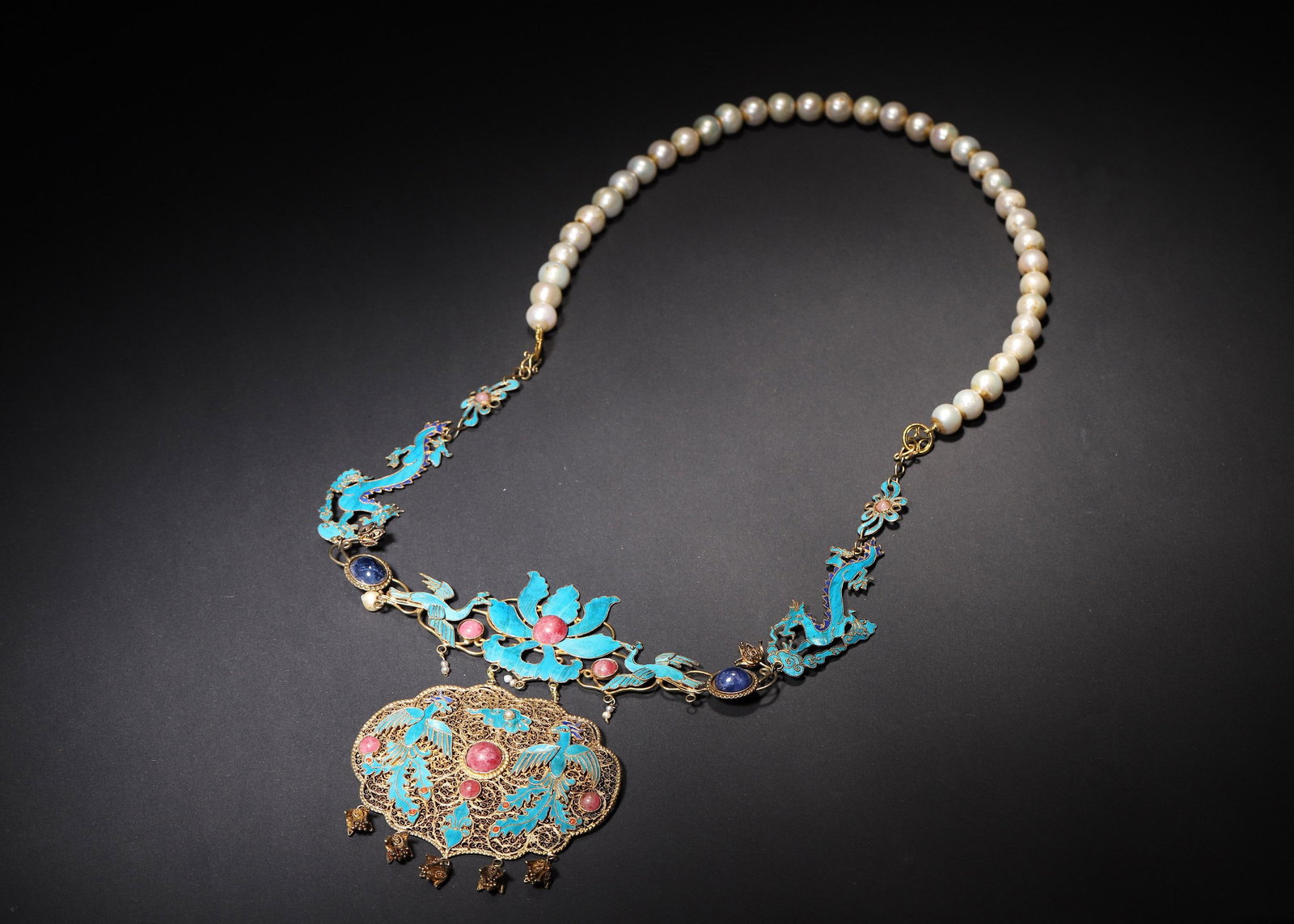 QING DYNASTY GILT-SILVER KINGFISHER FEATHER AND GEM-SET PHOENIX PENDANT NECKLACE WITH PEARL STRAND: 14.17in x 7.09in (36.0cm x 18.0cm), 0.293lb (133.0g)A fine Qing Dynasty gilt-silver necklace with kingfisher feather phoenixes, gem inlays, and pearl strand. Features intricate filigree, dragon motifs