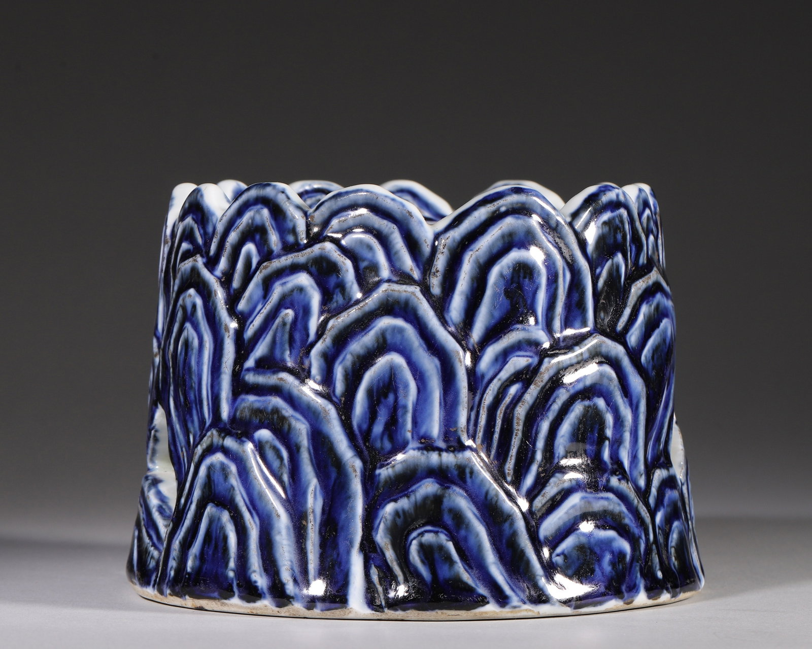 A BLUE AND WHITE OPENWORK CENSER WITH MOULDED MOUNTAIN LANDSCAPE, XUANDE PERIOD MING DYNASTY: L 15cm (5.91 in); H 11cm (4.33 in),A Ming Xuande porcelain censer modelled as stacked mountains with undulating mountain rim. The exterior is moulded in relief with layered peaks shaded by graded coba