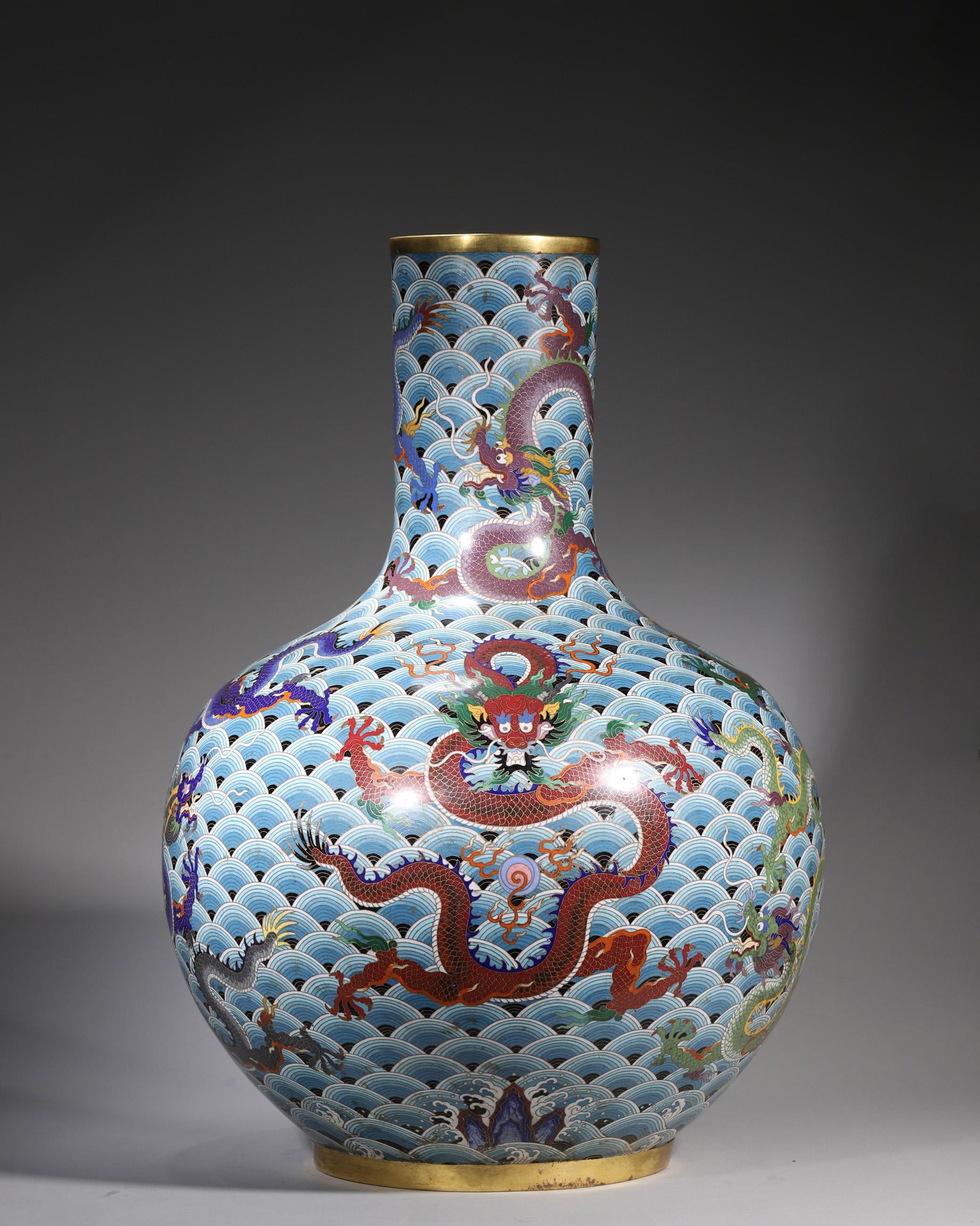 A Cloisonne Enamel 'Nine Dragons' Celestial Sphere Vase, Qing Dynasty: D 45.0cm (17.72 in); H 60.0cm (23.62 in); Wt 20.0kg (44.09 lb)A gilt-rimmed Qing Dynasty cloisonne enamel celestial sphere vase. Decorated with nine dragons in varied colours on a sea-wave ground, fea