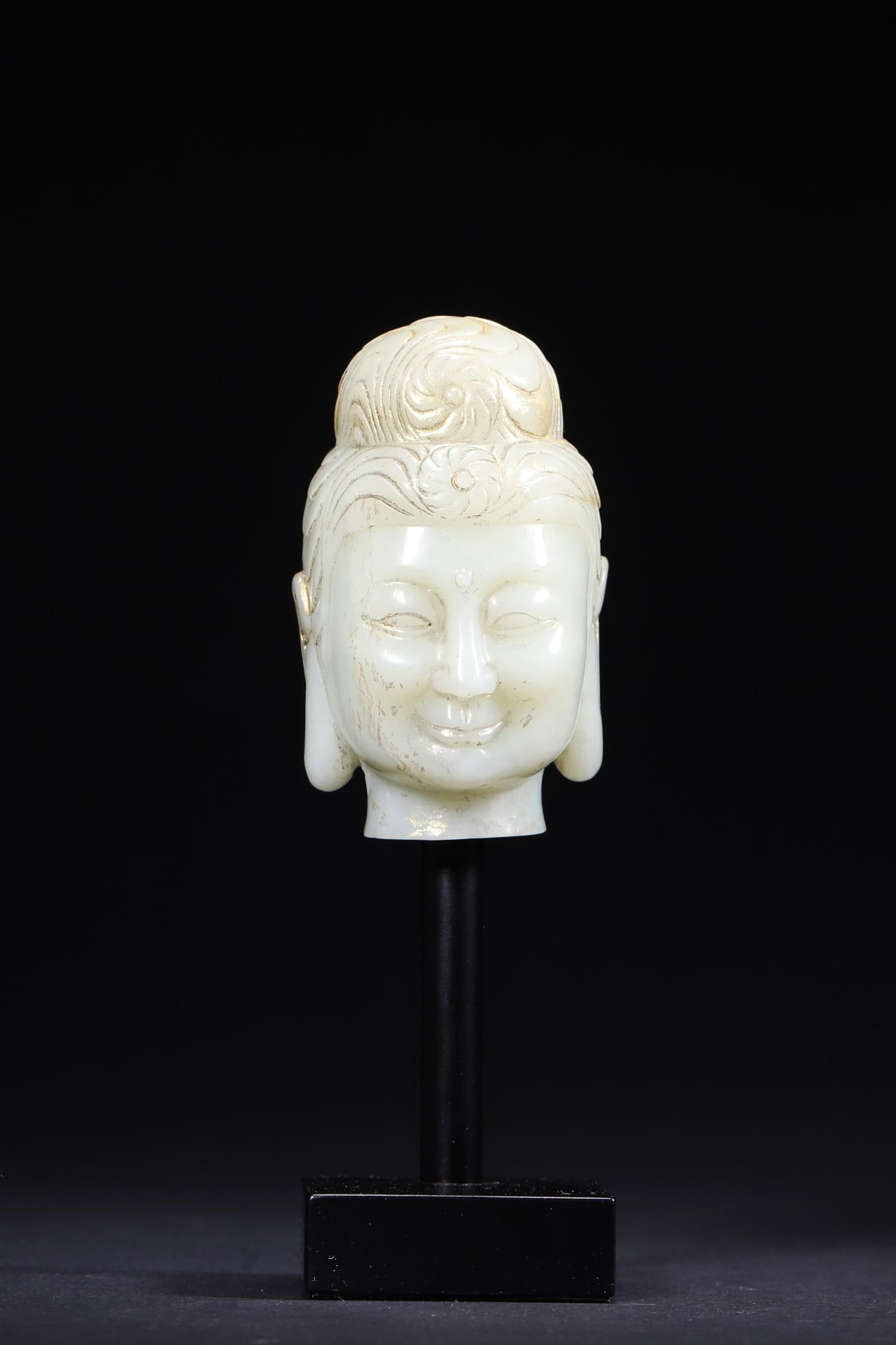 A Hetian White Jade Buddha Head with Gilded Details, Qing Dynasty: Length 5.1cm (2.01in), Width 5.5cm (2.17in), Height 8.5cm (3.35in), Weight 343.0g (0.76lb)This is a Qing Dynasty Hetian white jade Buddha head with gilded details. Carved with serene features and gild