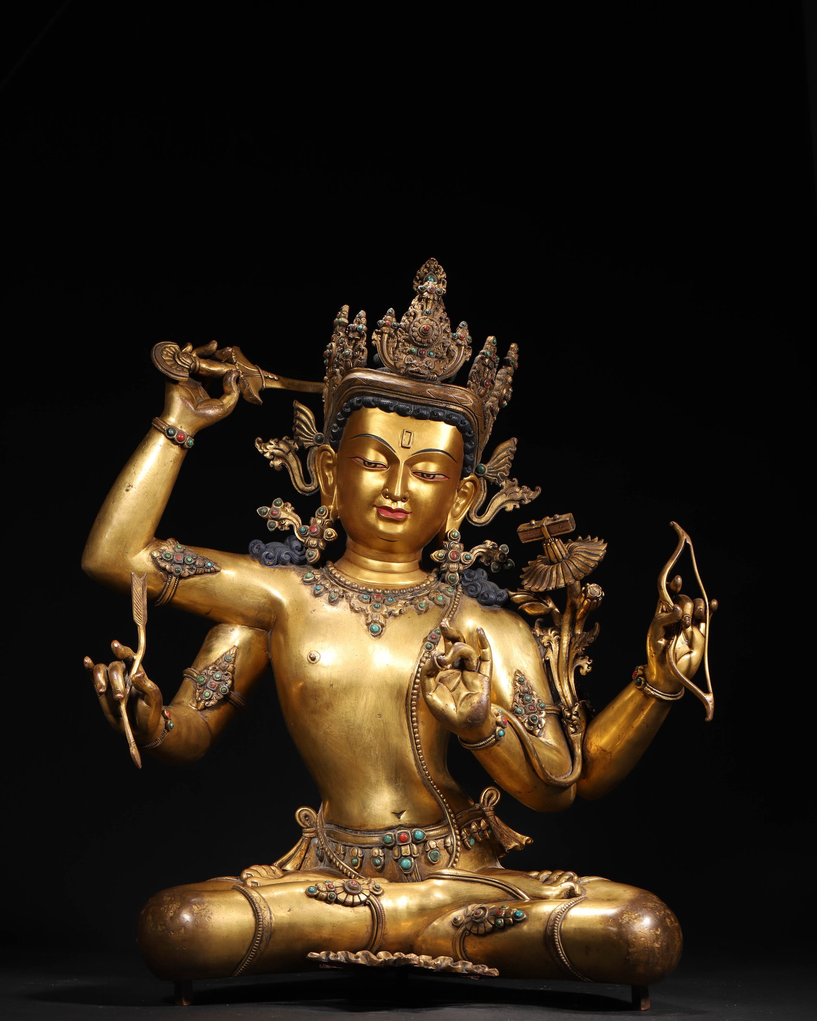 GILT-BRONZE INLAID FOUR-ARMED MANJUSHRI, QIANLONG PERIOD, QING DYNASTY: 17.32" x 9.84" x 20.47" inches (44.0 cm x 25.0 cm x 52.0 cm) (Main) | Weight: 31.53 lbs (14300.0 g)An gilt-bronze statue of Four-Armed Manjushri, made in the Qianlong period of the Qing Dynasty. Holdi