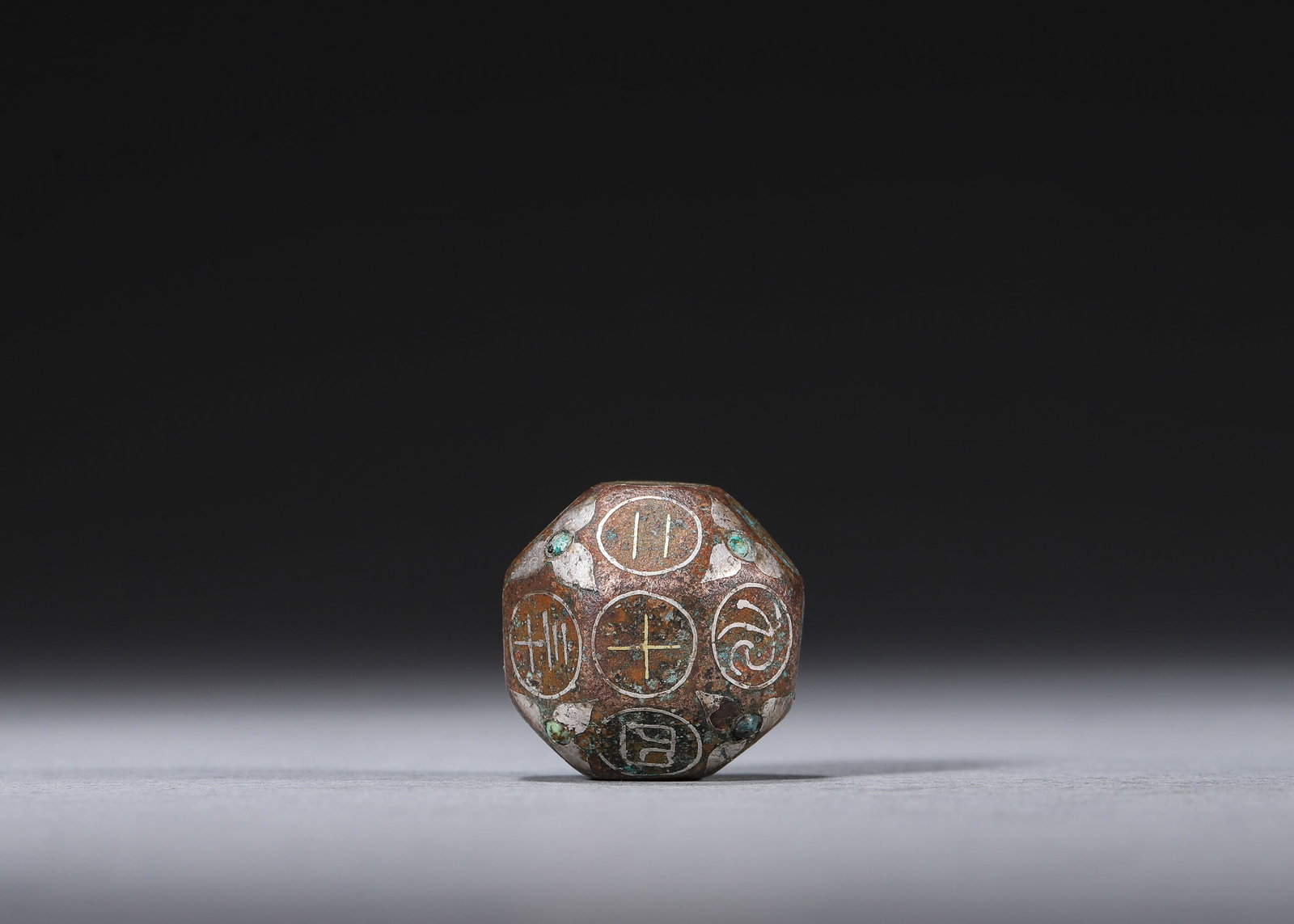 Han Dynasty Bronze 18-sided Gaming Dice, Inlaid Silver & Turquoise: W 2.20cm (0.87 in); Wt 50.00g (0.11 lb)An 18-sided bronze gaming die from the Han Dynasty for ancient bo game. Each face is inlaid with silver seal script characters, and turquoise stones are embedded