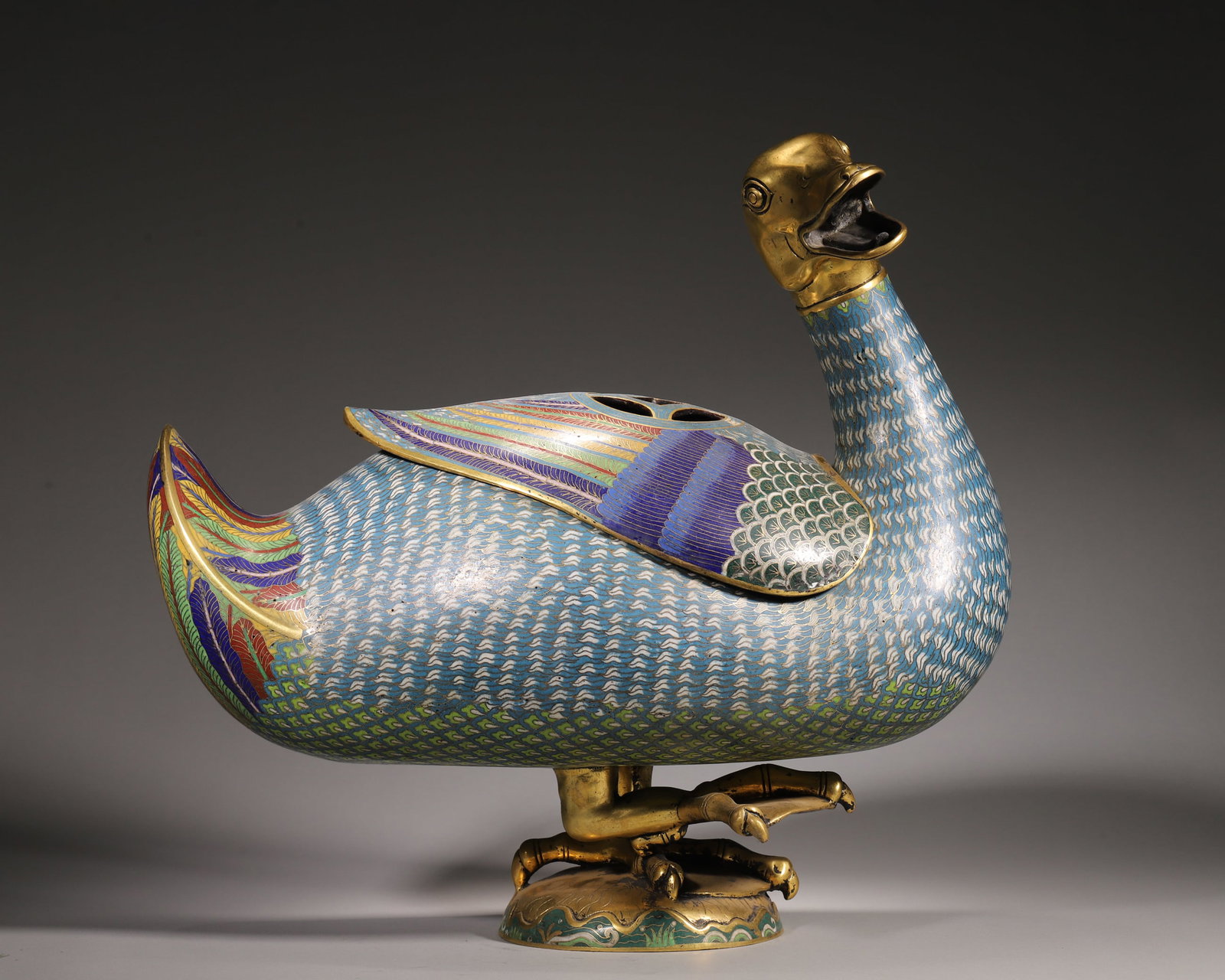 A Gilt Bronze Cloisonne Duck-Form Censer, Qing Dynasty: L 38.0cm (14.96 in); W 18.0cm (7.09 in); H 36.0cm (14.17 in); Wt 12.0kg (26.46 lb)This duck-form censer is made of gilt bronze with fine cloisonne enamel. The duck stands with its head raised, its fea