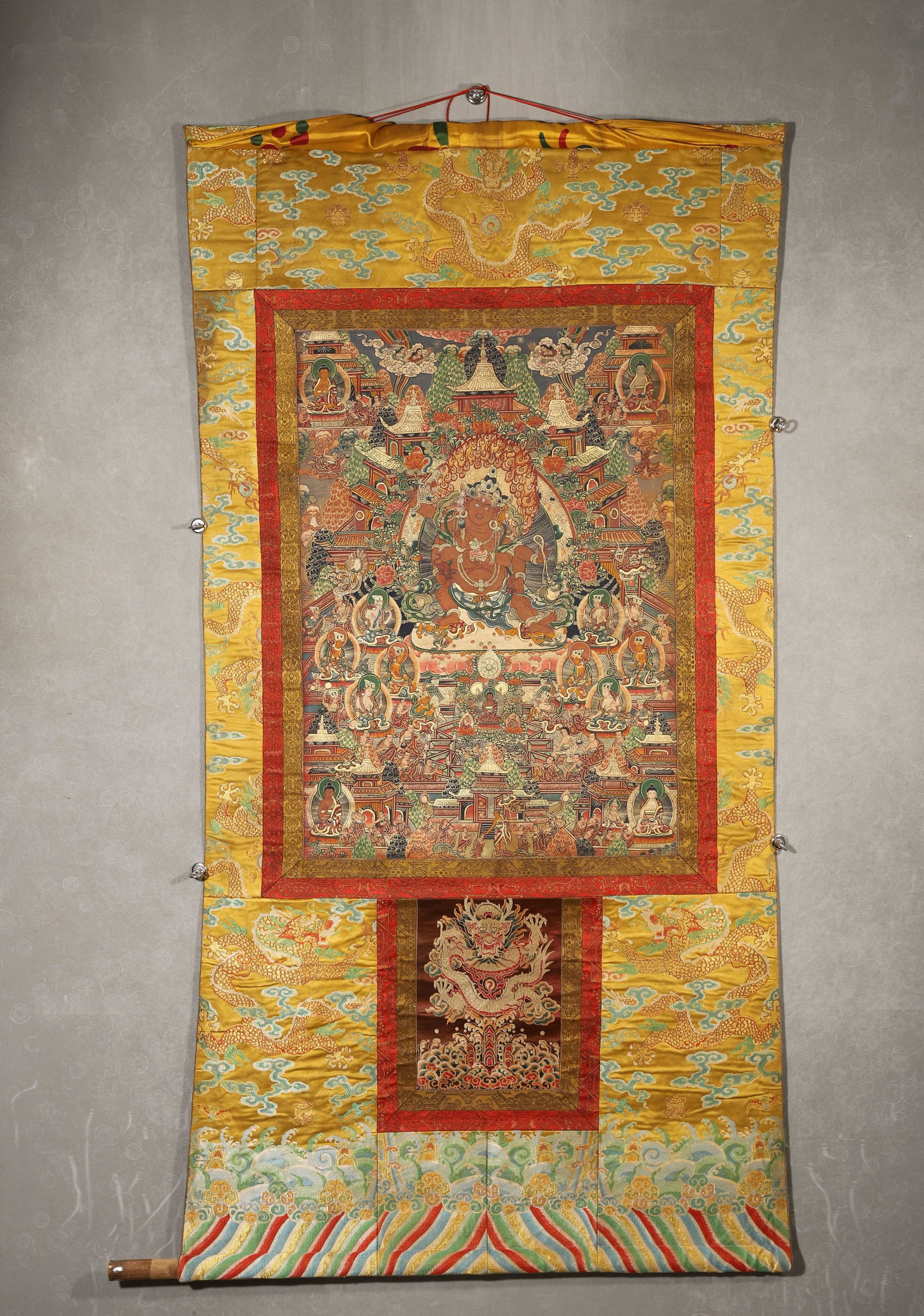 TIBETAN BUDDHIST THANGKA OF YELLOW JAMBHALA (IMPERIAL MOUNTING), 19TH CENTURY: 31.50in x 22.44in (80.0cm x 57.0cm)This 19th-century Tibetan Thangka depicts Yellow Jambhala in a pure land, crafted with vivid mineral pigments and gilded details. Mounted in imperial-style brocade