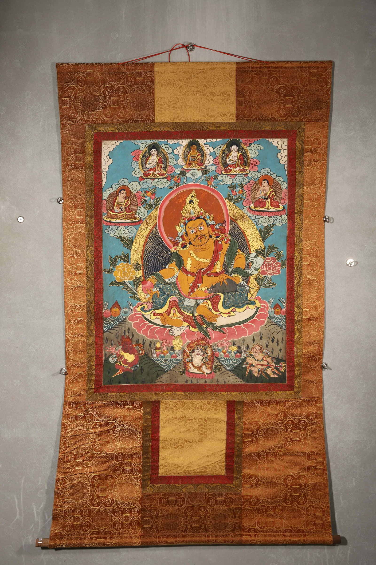 TIBETAN BUDDHIST THANGKA OF YELLOW JAMBHALA WITH TIBETAN MANTRAS, 19TH CENTURY: 35.43in x 26.77in (90.0cm x 68.0cm)This 19th-century Tibetan Thangka depicts Yellow Jambhala, crafted with vivid mineral pigments and gilded details. Tibetan mantras on the reverse confirm sacred