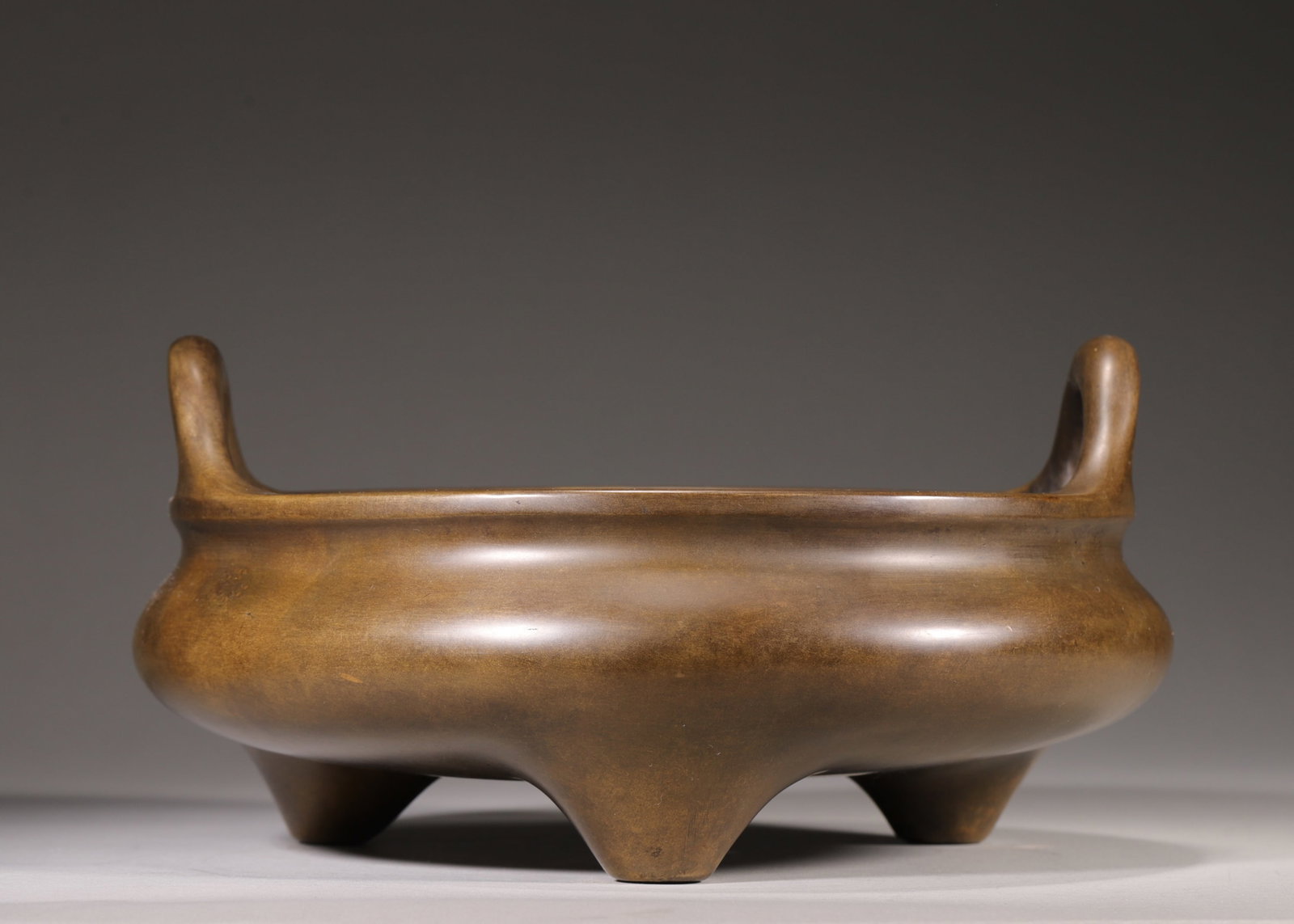 A Bronze Tripod Censer with Upright Handles, Marked "Xuan De Nian Zhi", Qing Dynasty: D 28.0cm (11.02 in); H 14.0cm (5.51 in); Wt 5529.0g (12.19 lb)A bronze tripod censer with upright handles, marked "Xuan De Nian Zhi", Qing Dynasty. Made of refined bronze with warm patina, it features