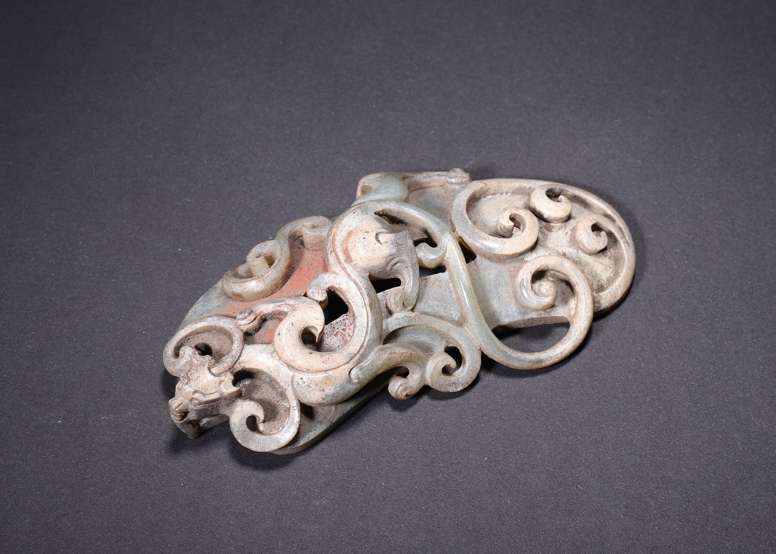 HAN DYNASTY, HETIAN CELADON WHITE JADE OPENWORK DRAGON & PHOENIX SHE PENDANT: L 10.00cm (3.94 in); W 5.00cm (1.97 in); Wt 92.00g (0.20 lb),Han Dynasty Hetian celadon white jade she pendant with shield form and central oval aperture. Multi-layer openwork interwoven dragon and ph