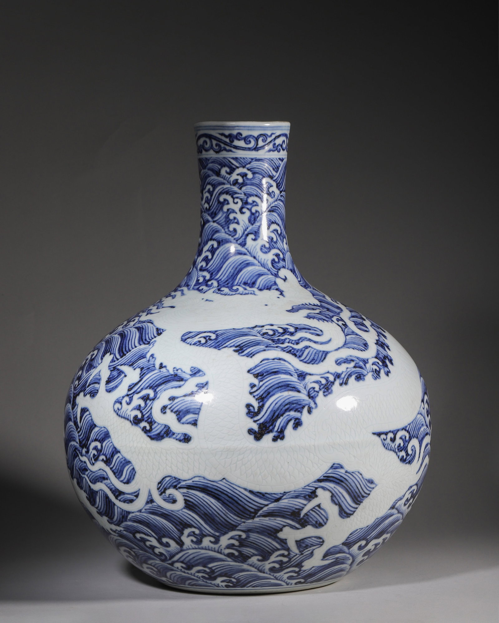 A BLUE AND WHITE INCISED DRAGON TIANQIU VASE, YONGLE PERIOD, MING DYNASTY: L 33cm (12.99 in); H 46cm (18.11 in),Ming Yongle period tianqiu vase with straight neck and unglazed sandy base. Neck decorated with scrolling vines, body covered with dense blue wave ground, reserved