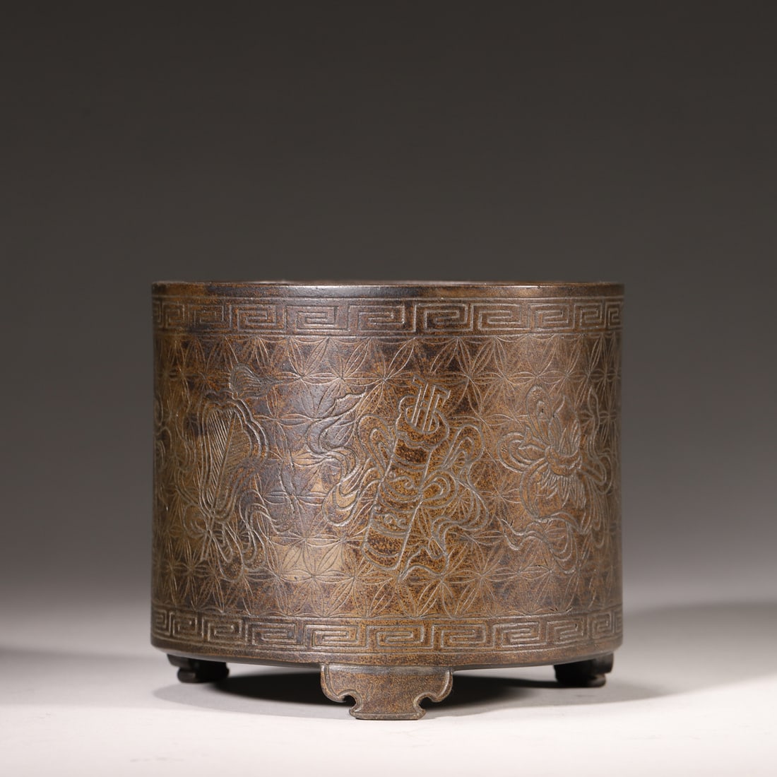 A BRONZE CENSER WITH ENGRAVED EIGHT TREASURES PATTERN, QING DYNASTY: Diameter 11.5cm (4.53in), Height 10.0cm (3.94in), Weight 738.0g (1.63lb),A cylindrical bronze censer from the Qing Dynasty, supported by three feet. The body is finely engraved with eight treasures pa