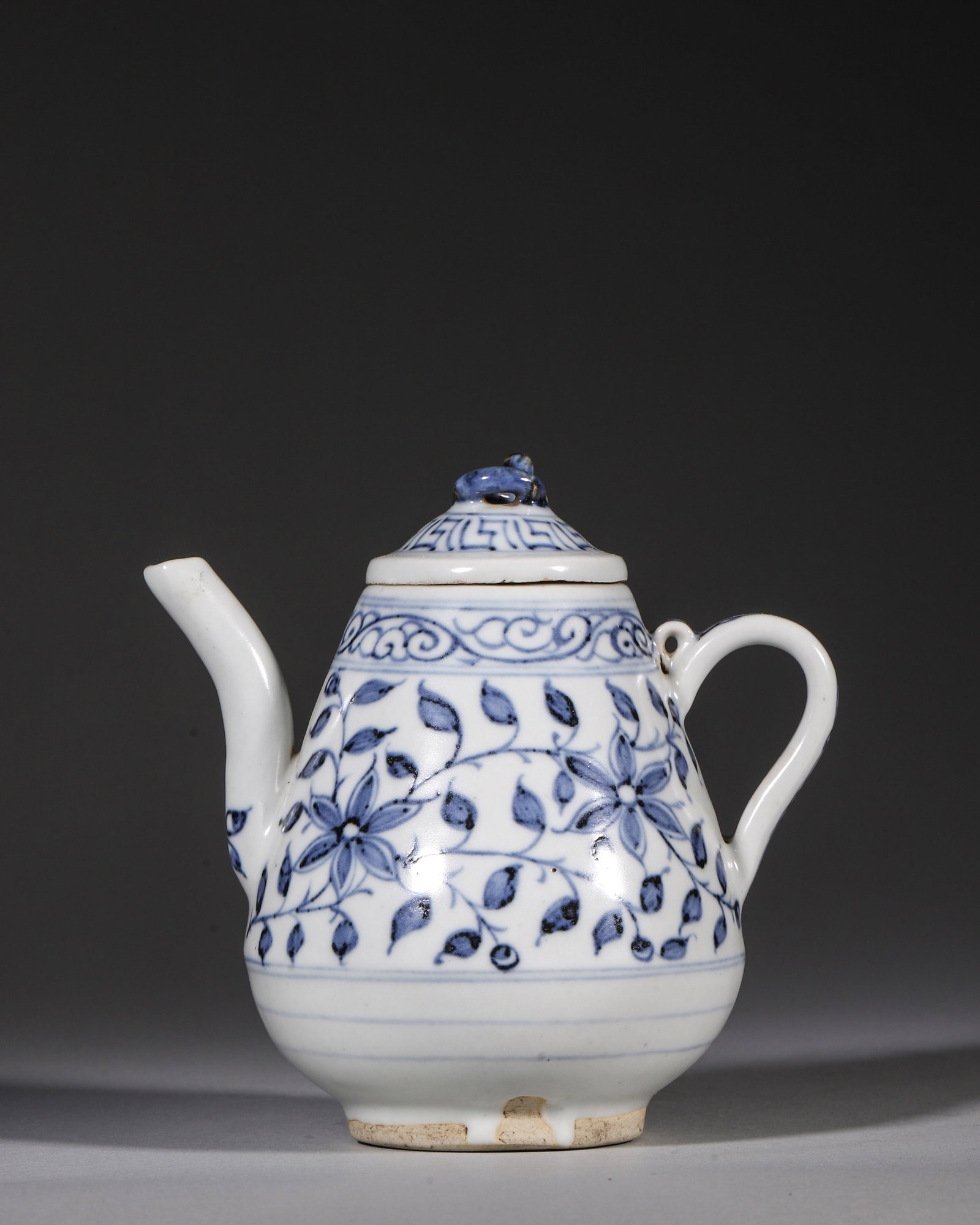A YUAN DYNASTY BLUE AND WHITE PEAR-SHAPED EWER WITH BEAST KNOB & INTERLOCKING FLORAL SCROLLS: L 12cm (4.72 in); H 12cm (4.72 in),A fine blue and white pear-shaped ewer from Yuan Jingdezhen kiln, with a beast-knobbed lid, graceful spout and handle. It is decorated with interlocking floral scrol
