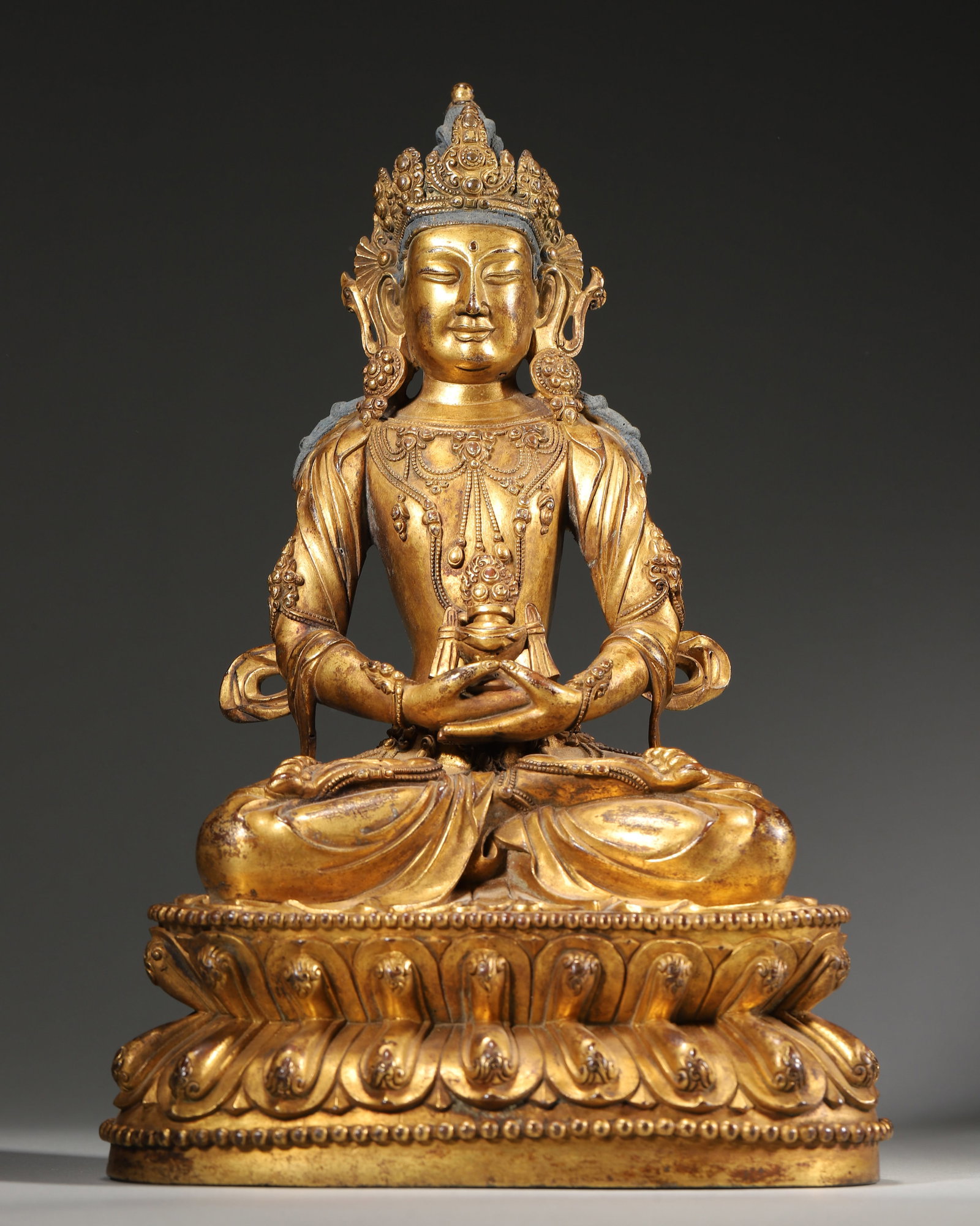 Qing Dynasty, Gilt Bronze Amitayus Buddha Seated Statue: Width 16.0cm (6.30in),Height 24.0cm (9.45in),Weight 2436.0g (5.37lb)Tibetan gilt brass Buddha statue of Qing period. Amitayus sits full-lotus on double-layer lotus base, holding longevity vase at abdo