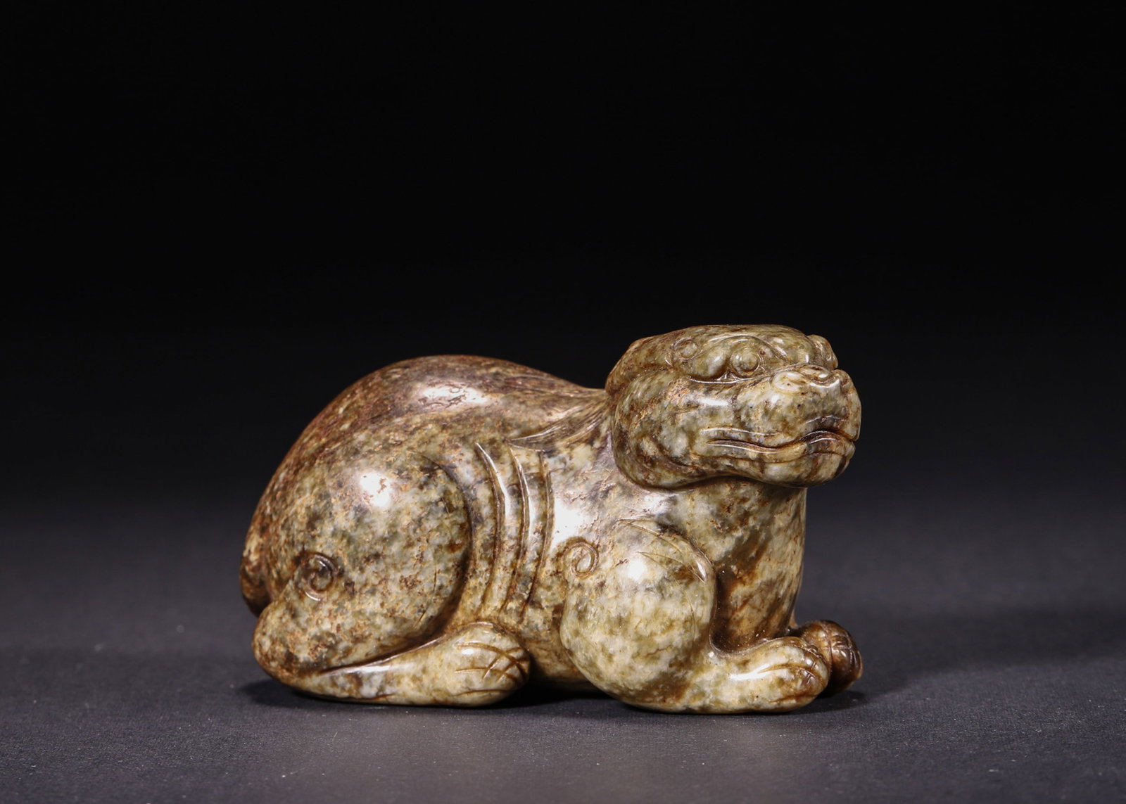 A Hetian Jade Mythical Beast Paperweight, Ming Dynasty: L 8.5cm (3.35 in); W 4.0cm (1.57 in); H 5.0cm (1.97 in); Wt 249.0g (0.55 lb)A Ming Dynasty paperweight carved from Hetian jade with rich patina. It depicts a plump recumbent mythical beast with smooth
