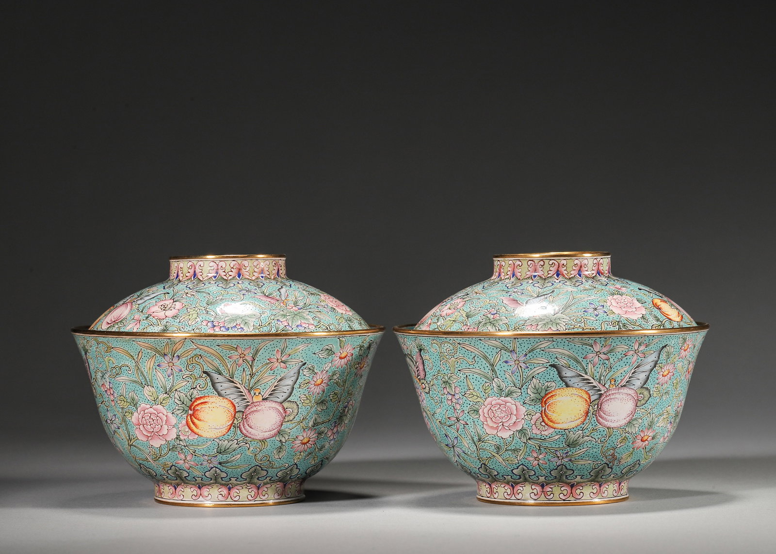 PAIR OF QIANLONG PERIOD, QING DYNASTY COPPER-BODIED ENAMEL LIDDED BOWLS WITH FRUIT AND FLOWER MOTIFS: 4.33in (11.0cm), 1.442lb (654.0g)A fine pair of Qianlong period copper enamel lidded bowls with turquoise ground, vibrant floral, butterfly and three abundances motifs, and gilt rims. Marked "Qianlong