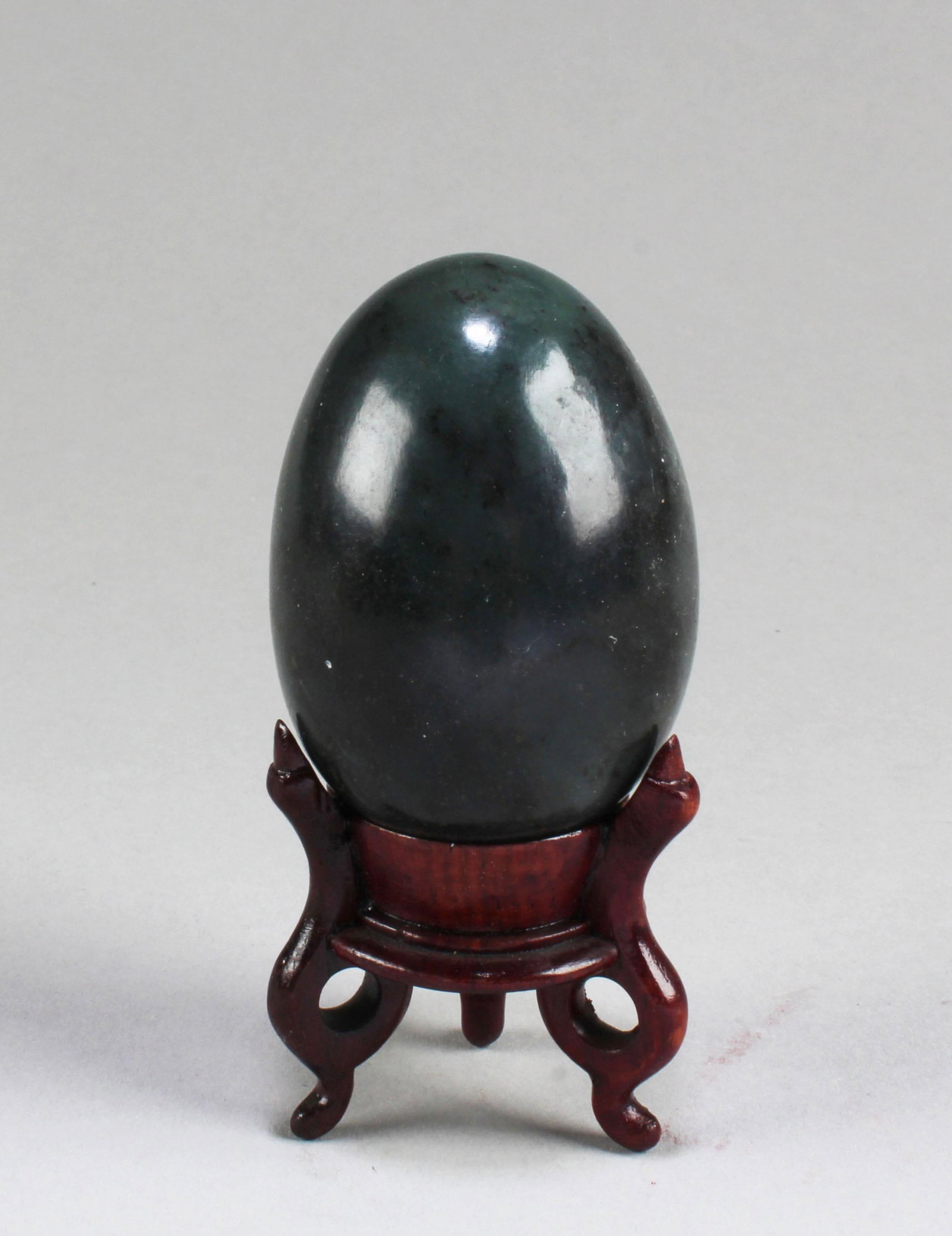A Jadestone Egg-Shaped Ornament: A Jadestone Egg-Shaped Ornament. Comes fitted with a wooden base. Length: 2.25"