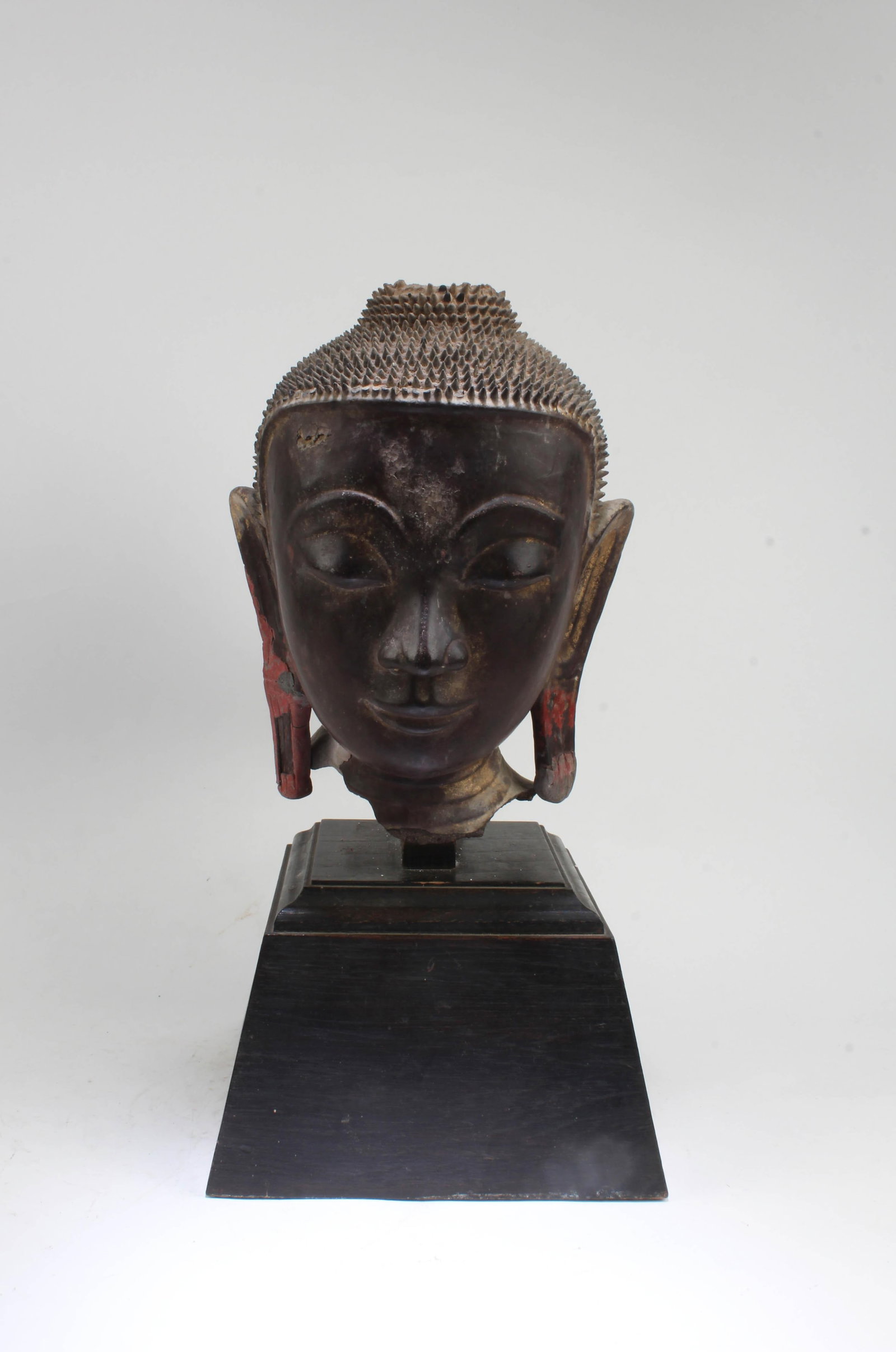A Clay Buddha Head: A Clay Buddha Head, with wooden stand. Height: 10.25" (Without stand) Height: 16" (With stand)Provenance: From Pasadena Antique Centre