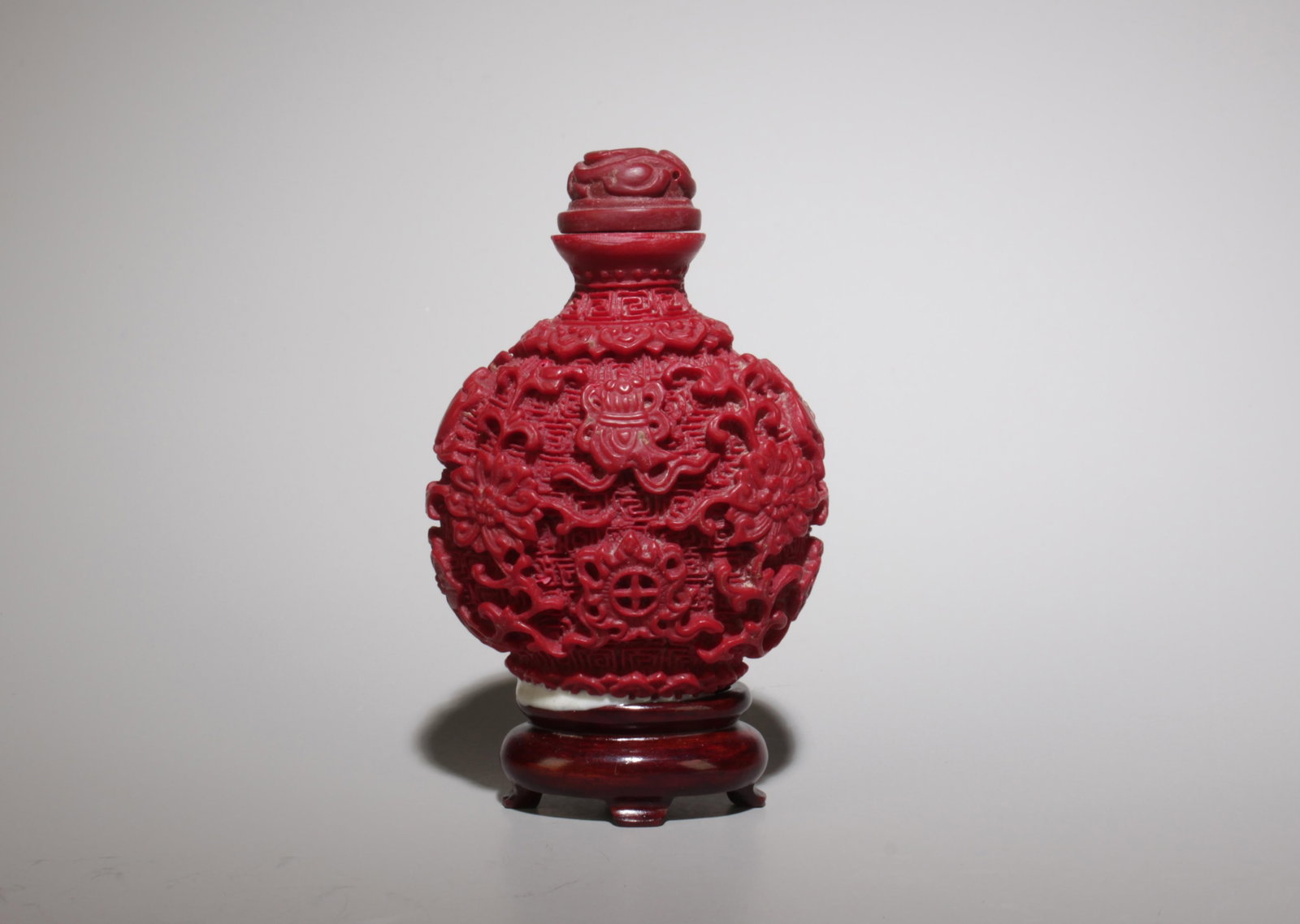A Cinnabar Snuff Bottle w/ Stand: A Cinnabar Snuff Bottle w/ Stand. (no stand) Dimensions: 2.75" x 2.1".