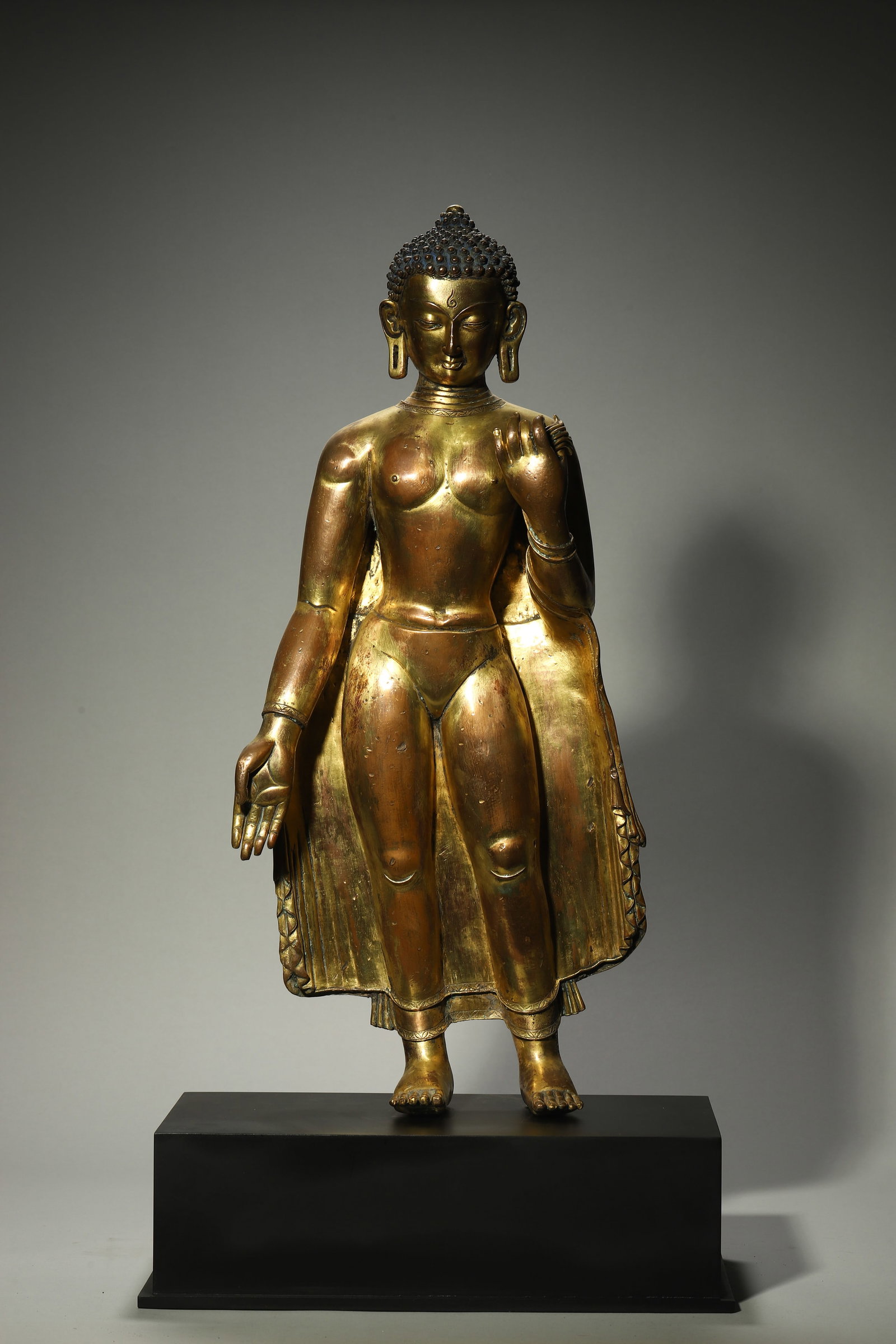 A Gilt-Bronze Standing Shakyamuni Statue of Early Malla Period: A Gilt-Bronze Standing Shakyamuni Statue of Early Malla Period. Height: 22.05in; Width: 9.84in.