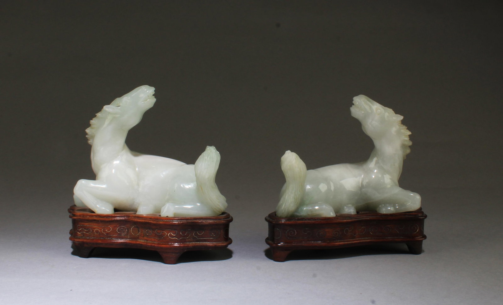 An Antique Pair of Carved Jadeite Jade Figurines: Antique Pair of Carved Jadeite Jade Horse Figurines. Comes fitted with a wooden stand each. Length: 3.75"