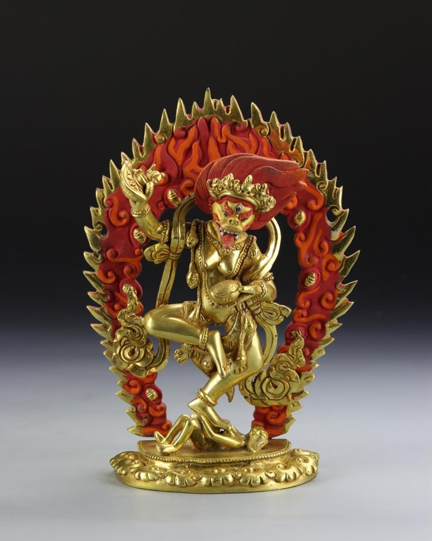 Tibetan Gilt Buddha: Tibet, gilt Buddha, in standing position, with flowing robes, holding objects, with painted red lotus border attached to base. Height 7 3/8 in.