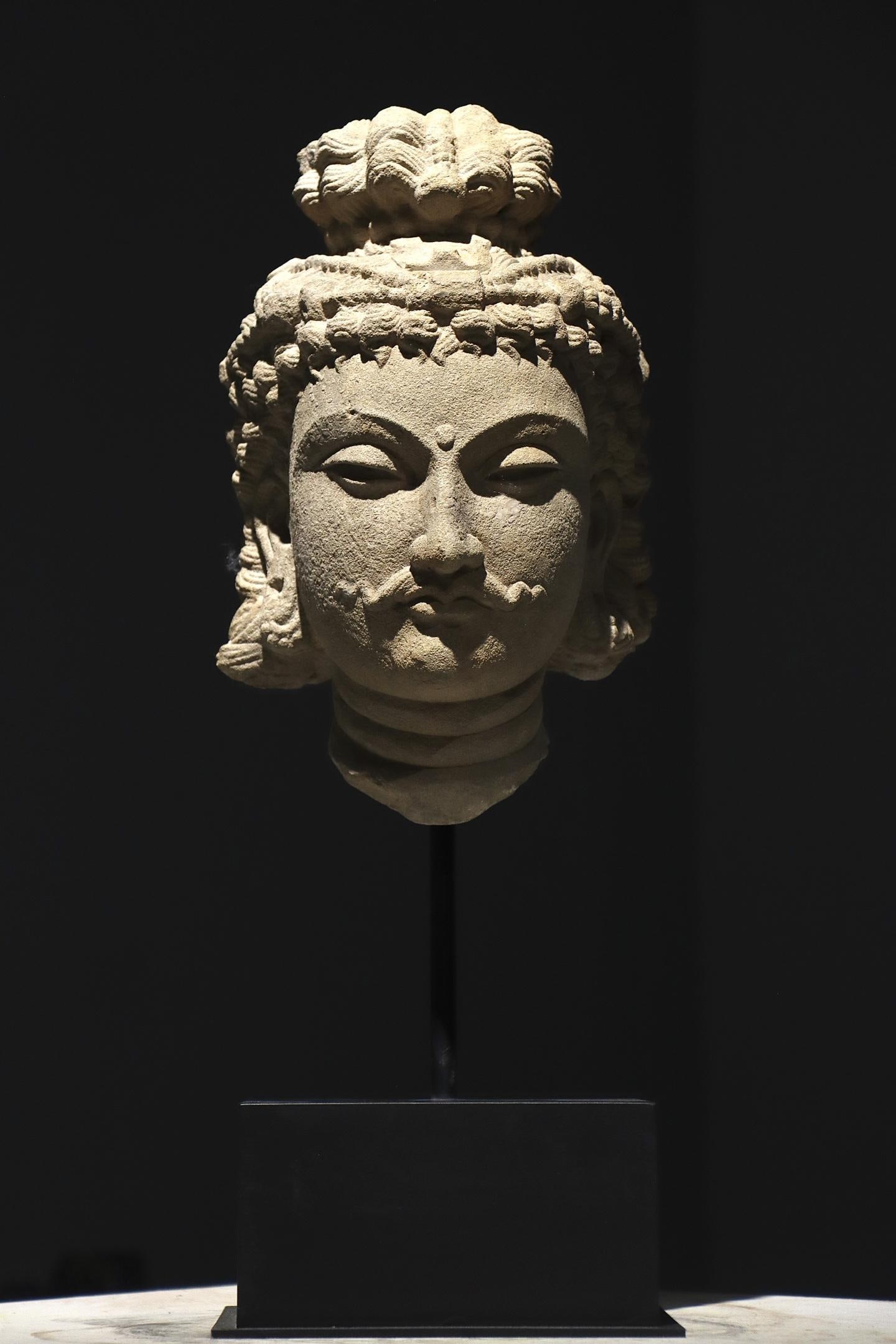 3RD CENTURY GANDHARA STYLE SANDSTONE BODHISATTVA HEAD: 3RD CENTURY GANDHARA STYLE SANDSTONE BODHISATTVA HEAD. Height:54cm(21.26in), Height:33cm(12.99in)Sandstone Bodhisattva head of Gandhara style. The sculpture features elaborate wavy hair and high