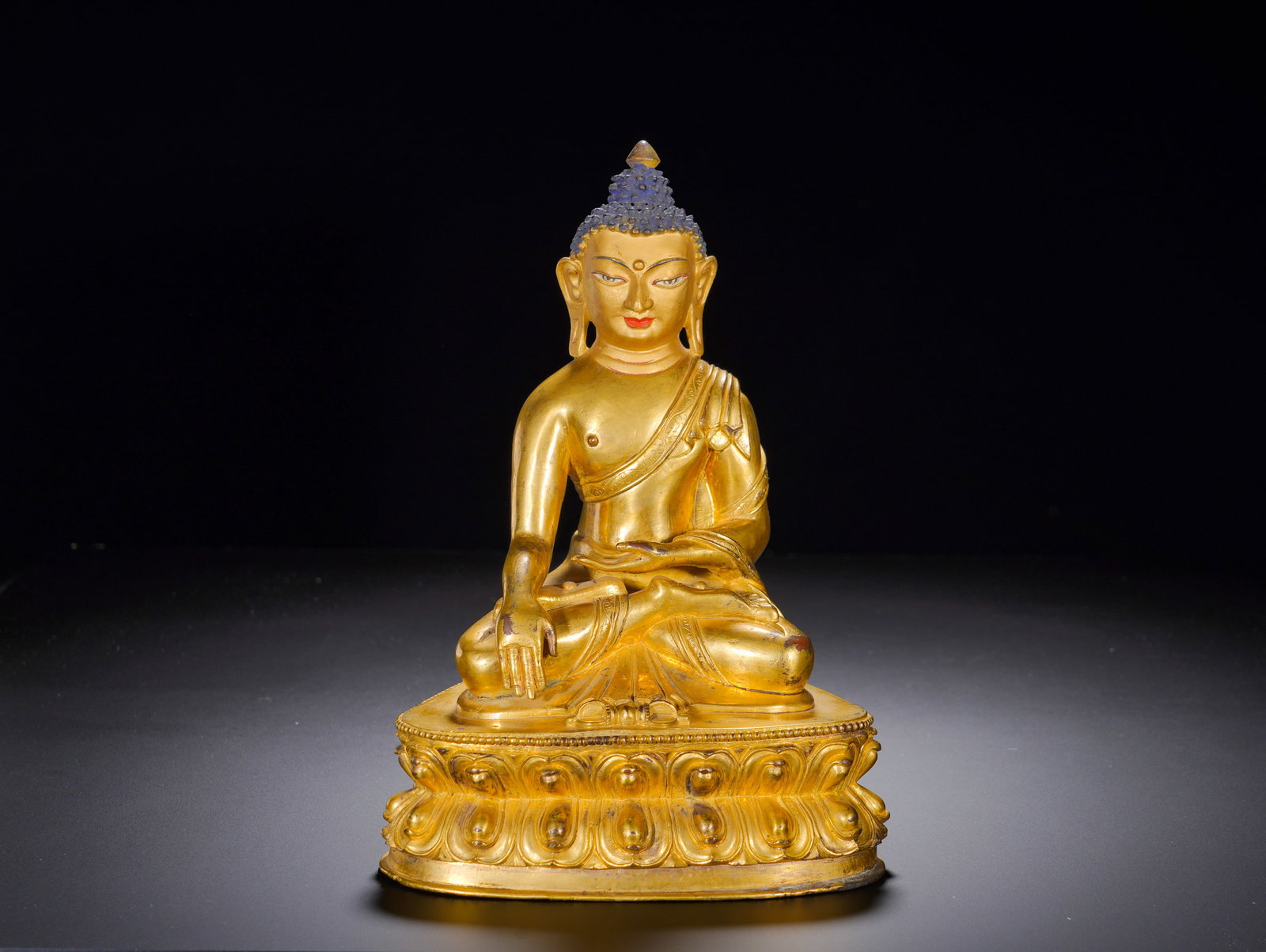 A GILDED BRONZE STATUE OF SAKYAMUNI BUDDHA FROM THE QING DYNASTY: A GILDED BRONZE STATUE OF SAKYAMUNI BUDDHA FROM THE QING DYNASTY. Height:22cm(8.66in), Width:17cm(6.69in), Weight:2820g (6.217lb)Cast gilt bronze figure of Shakyamuni seated in full lotus posture on d