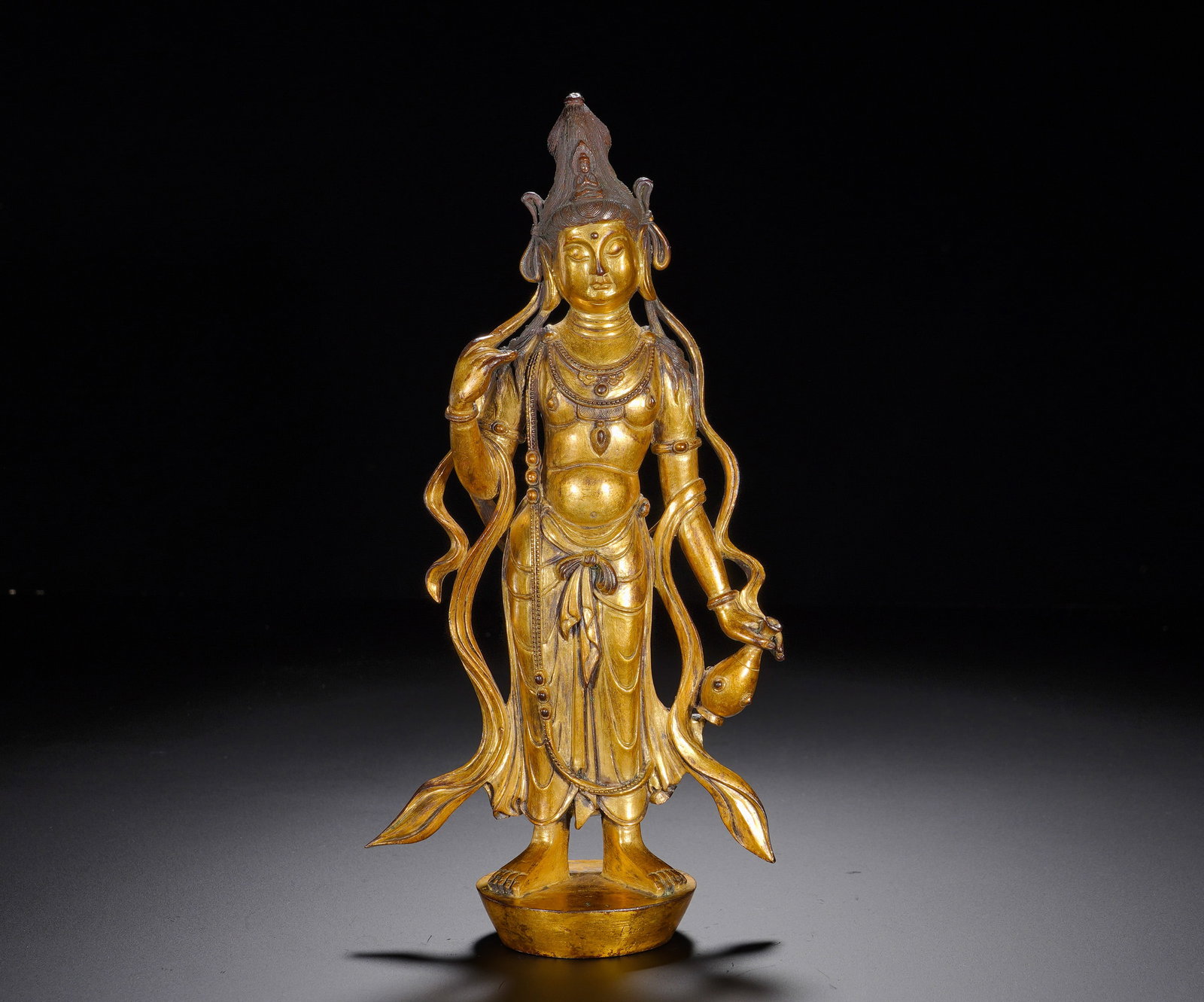 A STANDING STATUE OF GUANYIN IN A GILDED BRONZE VASE FROM THE TANG DYNASTY: A STANDING STATUE OF GUANYIN IN A GILDED BRONZE VASE FROM THE TANG DYNASTY. Height:22cm(8.66in), Width:11cm(4.33in), Weight:960g (2.116lb)Vase-bearing Avalokiteshvara symbolises compassionate
