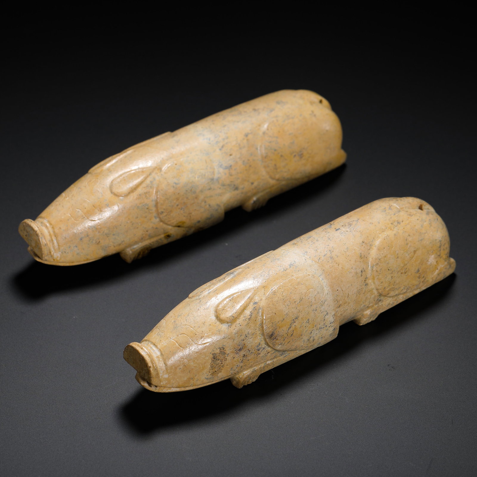 A PAIR OF JADE PIGS FROM THE HAN DYNASTY: A PAIR OF JADE PIGS FROM THE HAN DYNASTY. H:3cmW:12.2cmWeight:430g Funeral jade pig holders of Han Dynasty, fully calcified into chicken bone white, held by the deceased to symbolize wealth and abunda
