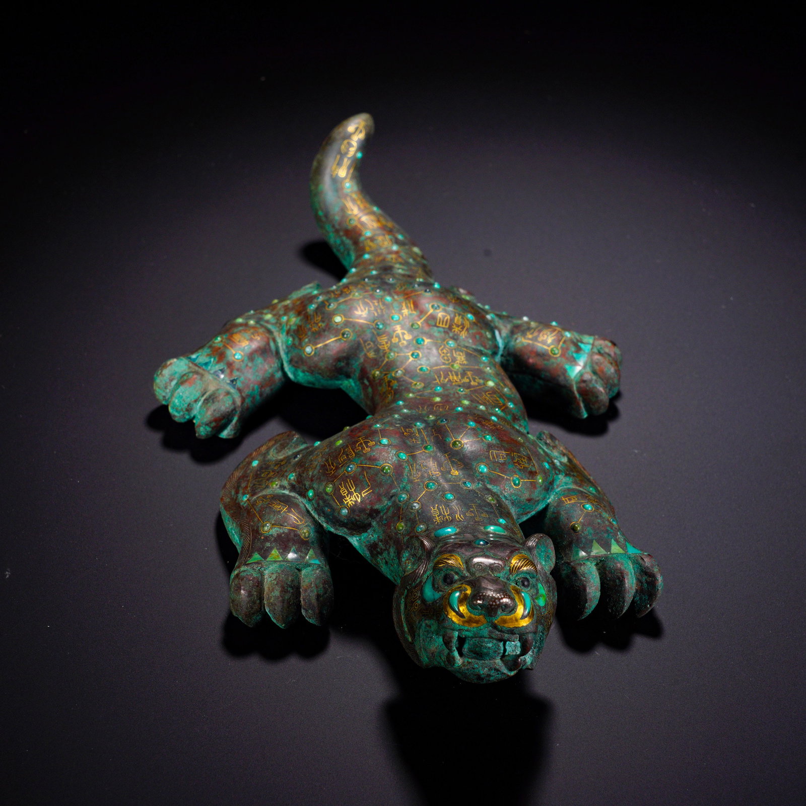 BRONZE FROM THE WARRING STATES PERIOD INLAID WITH GOLD AND PINE STONE TIGER-SHAPED ASTRONOMICAL: Length:15cm(5.91in) Width:27cm(10.63in) Weight:2225g(4.906lb)Cast in the form of a recumbent tiger with raised head, open mouth and bared teeth, the beast has a robust body, stretched limbs and an upt