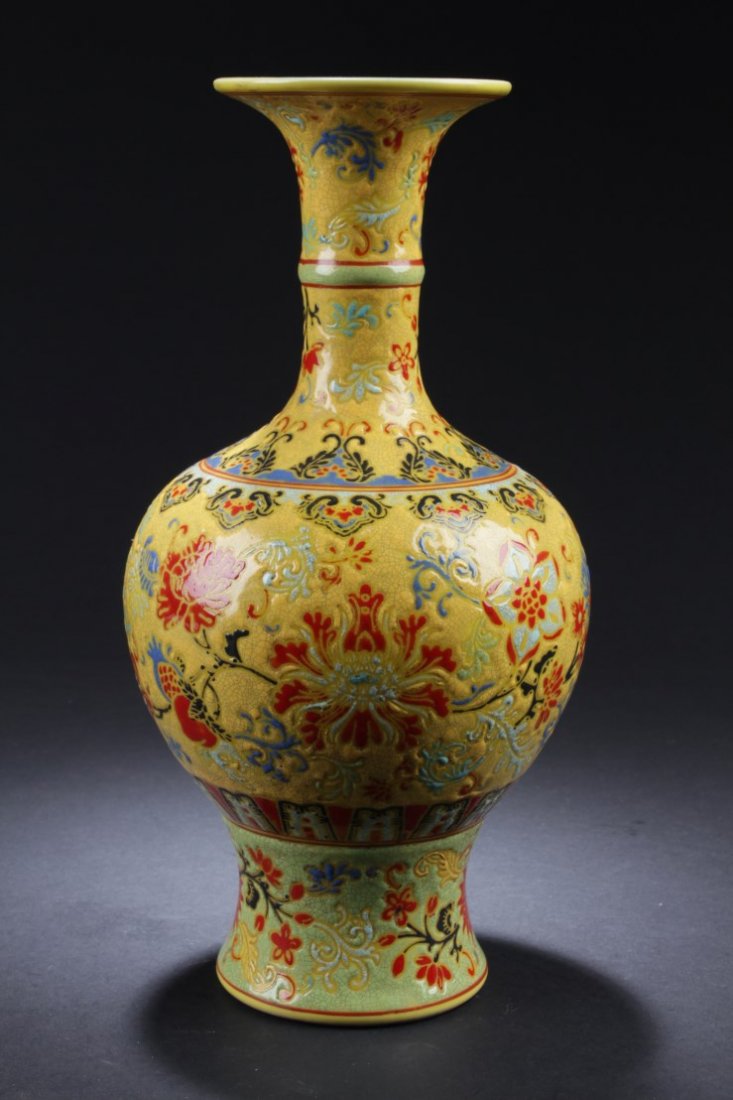 Chinese Porcelain Vase: Of broad shoulders rising to a tall trumpet neck, the vase is decorated with floral patterns, covered overall with yellow color. A six character mark is imprinted at the bottom. Height: 11 "
