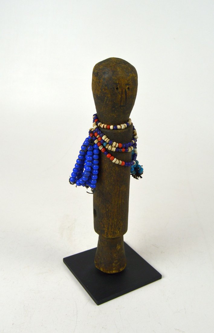 Old Wooden Fulani Doll, African Art: This is a sweet and simple old wooden doll from the Fulani peoples, Nigeria. A carved post like sculpture with hand strung beads attached as "arms". The doll has been mounted to a metal display stand 