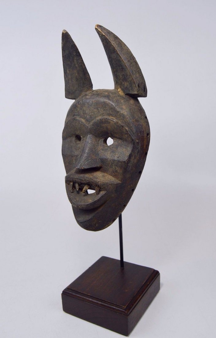 Old Dan Horned Mask, African Art: A bold and powerful old Dan mask from the Cote De Ivorie of West Africa. A carved wooden mask with exaggerated horns and stylized teeth. The mask has well handled edges and interior. The mask itself m