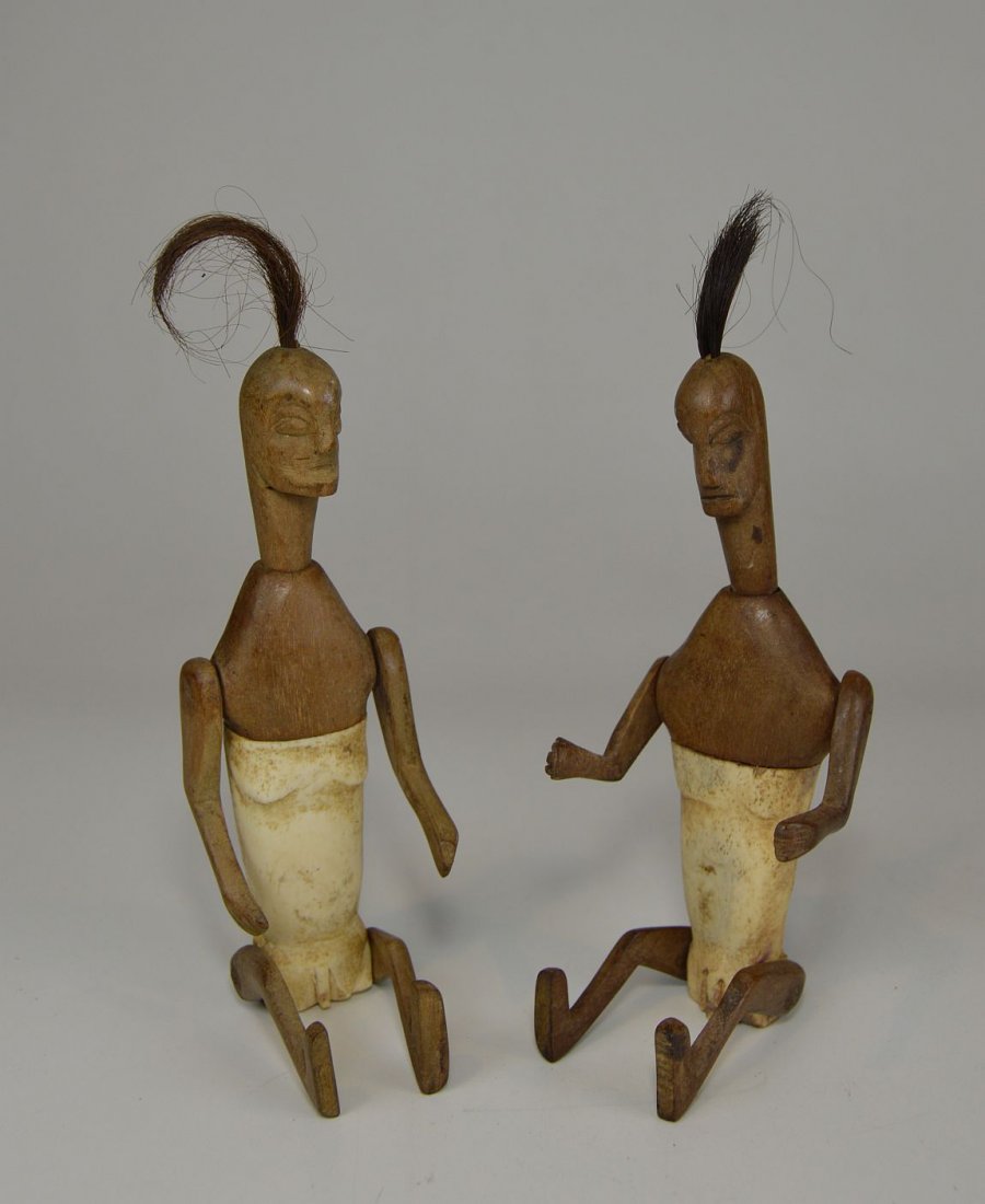Pair of Articulated Bone and wood dolls from Timor isle: Carved wood and bone dolls from Timor island, Indonesia. A pair of articulated dolls and ornate carved animal designs on their backs. From Timor island or related culture, Indonesia.
