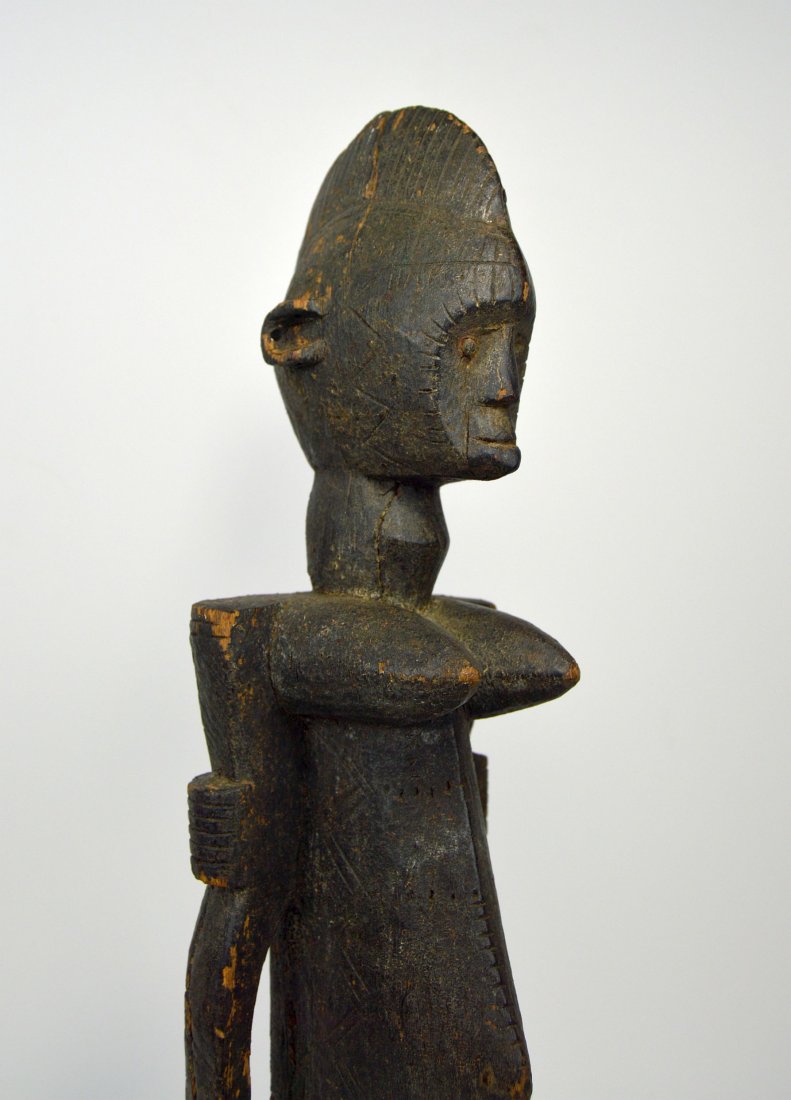 A Dogon female ancestor sculpture: A carved wooden female ancestor in a bold archaic style with incised linear designs, and an overall stylized form. Dogon peoples, mali, Africa. A vintage to antique example that measures 22 inches tal
