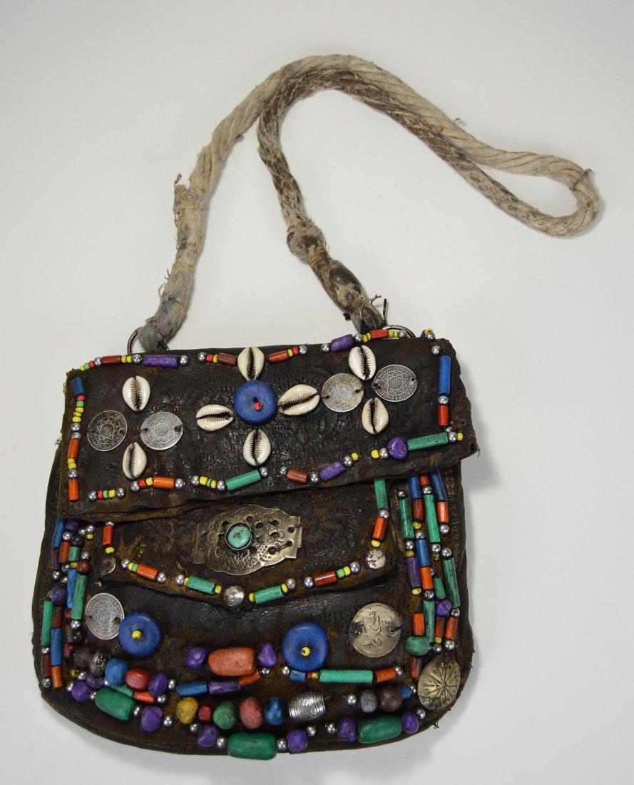 Vintage Berber leather bag with Ornate regalia: This is a highly decorated old leather satchel from the berber peoples of North Morocco, Africa. The leather bag was carried by berber men while traveling and has been decorated with various coins, sh