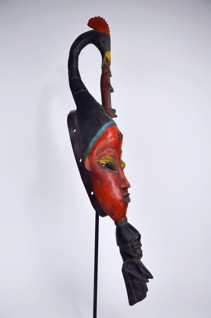 Vintage Red Guro Stylized African mask: Fantastic and exaggerated carved wooden mask with stylized mask featuring a tall finial with long neck bird eating a fish and an ancestral bust on the chin. Guro peoples, Ivory Coast, Africa. Measures