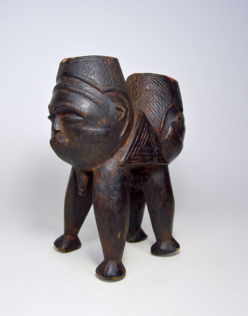 A Unusual janus-form male & female Kuba Palm wine cup: carved wooden double beaker with male and female cups around a central Triangle motif accented with incised linear designs. Kuba peoples, Congo, Africa. The Cup measures 8.75 x 7.75 inches.