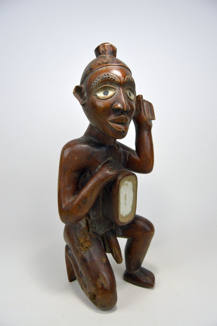 A Handsome kneeling Kongo male ancestor sculpture: Carved wooden male "magic" effigy shown kneeling on a knee with hand in the air and the other hand resting on the magic bundle sealed within the chest cavity with a mirror. Kongo peoples, Congo, Afric