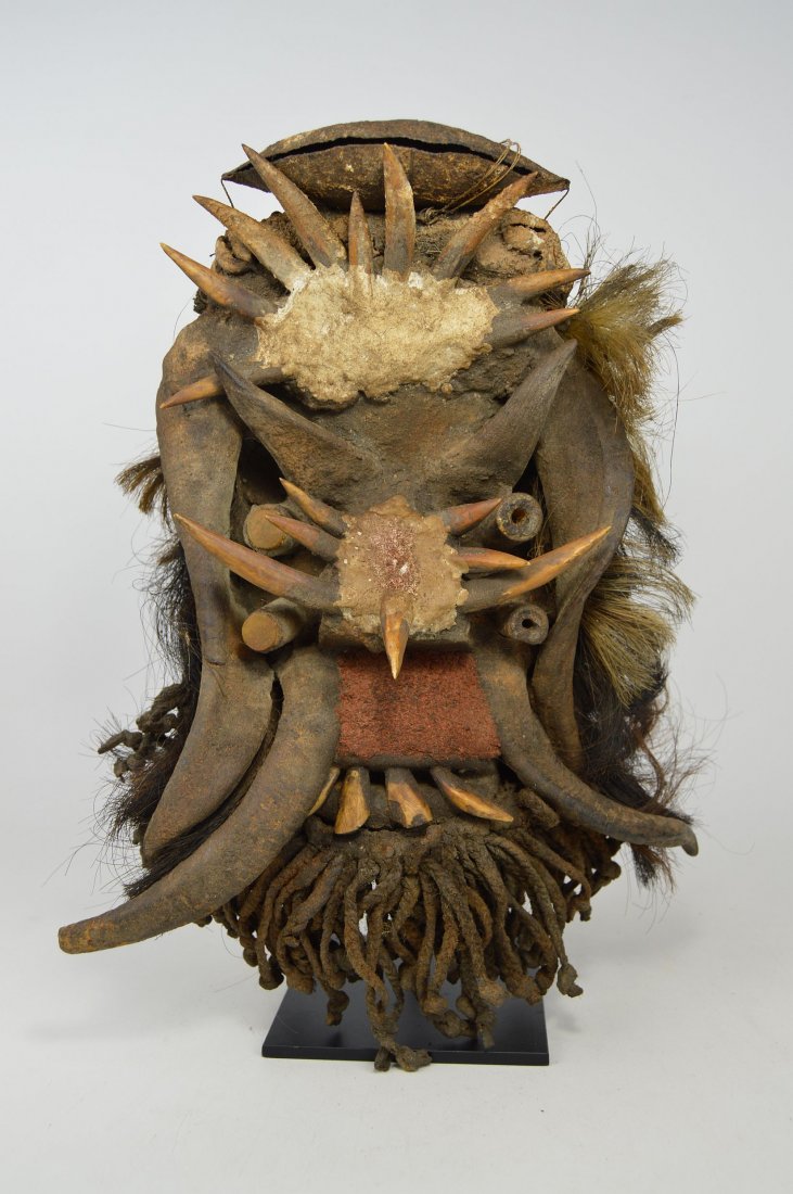A Gere fetish mask, African Art & Magic: Carved wooden mask with various accoutrements such as goat horns and bone spikes and animal hide. Gere peoples , Liberia, Africa. The mask display stand can be included for an additional $34.00. The m