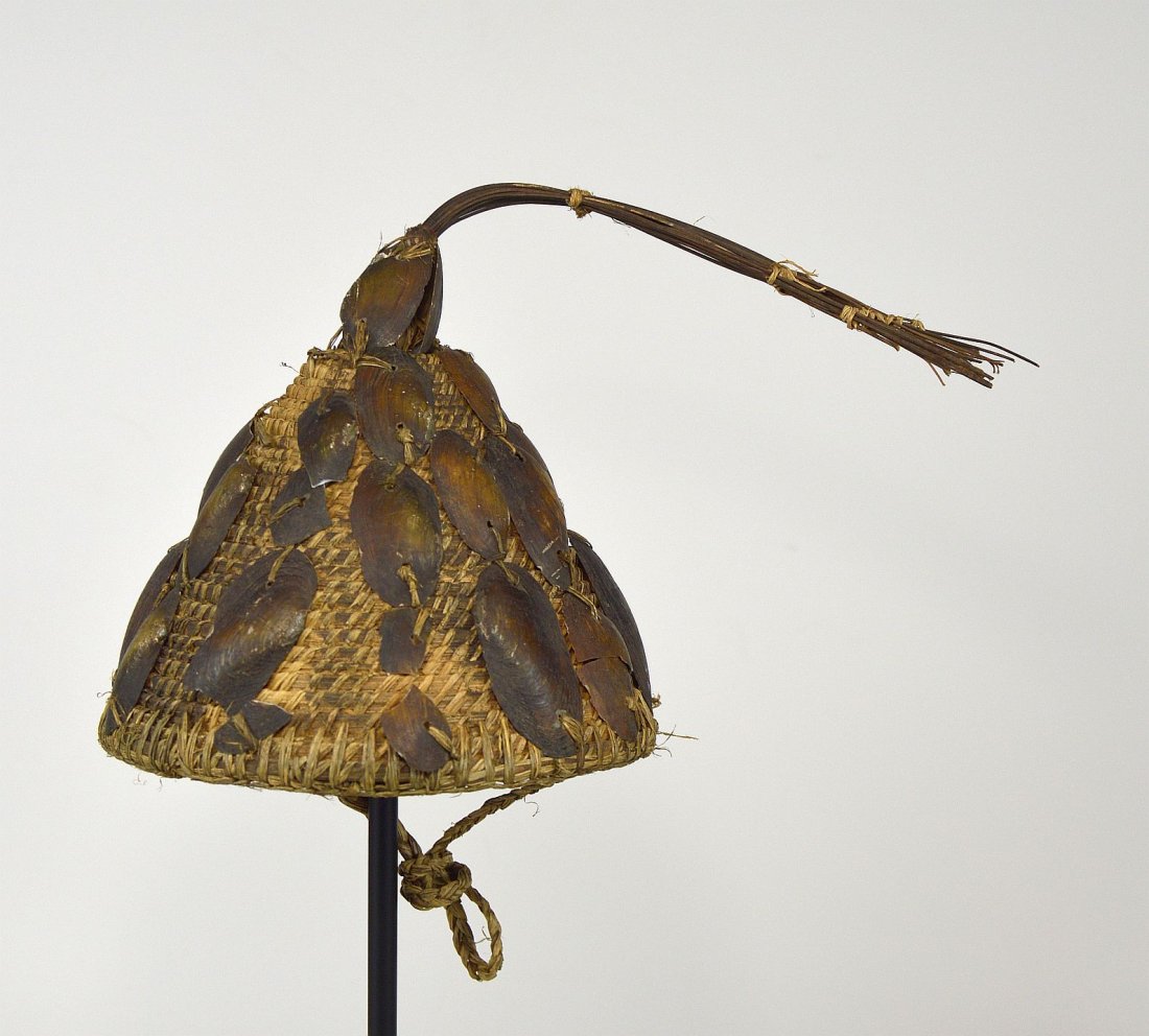 A Lega Woven Grass hat with Shells, African Adornment: Wonderful old woven grass conical cap with river shells attached and some stiff grass as finial, with woven strap for wearing. Lega Peoples, Congo, Africa. The hat measures 8x7 inches, not counting to