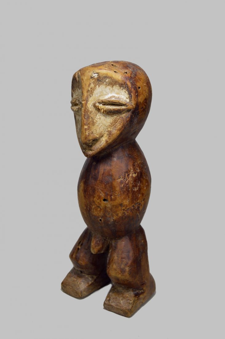 LEGA KAKULA KA MPITO SCULPTURE: A finely carved wooden sculpture of Kakula Ka Mpito or "Old one" with traditional face accented with kaolin clay pigment and a golden honey brown patina on minimalist form. According to research, the 